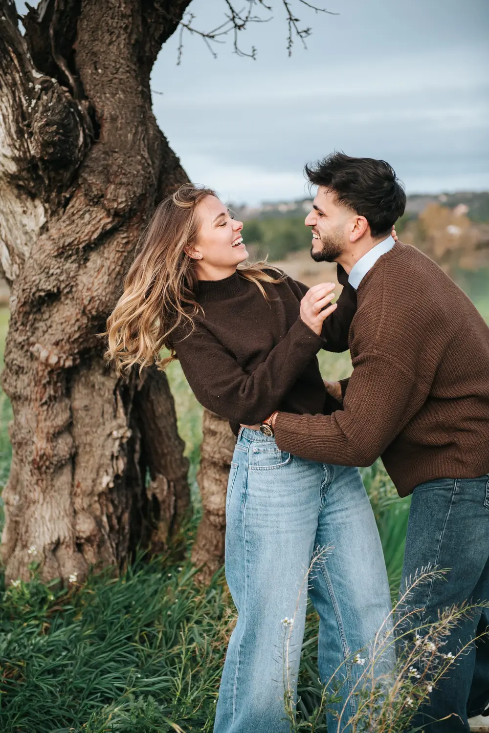 Couple qui rit contre un olivier, émotion naturelle pendant une séance photo