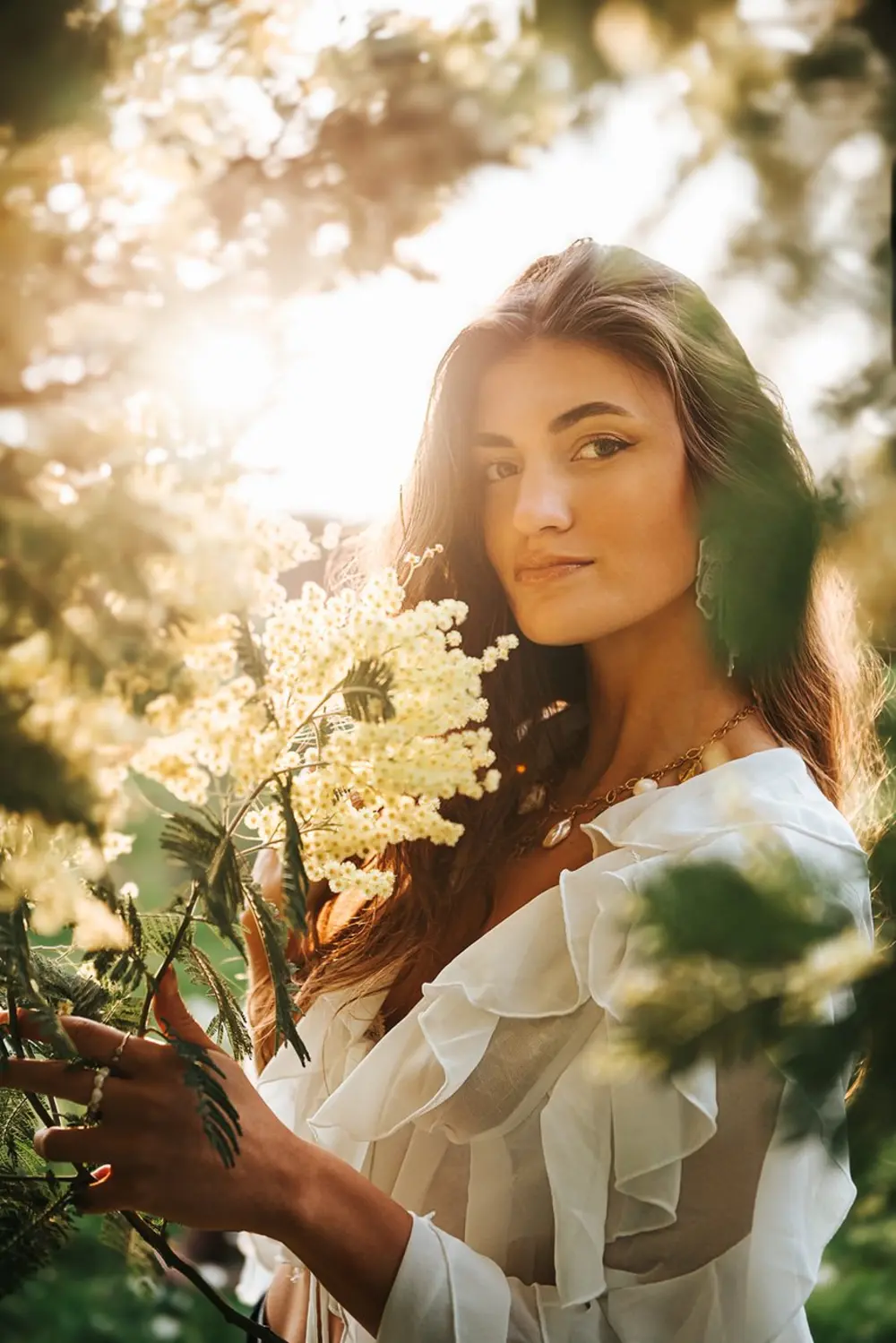 Portrait de femme en lumière dorée parmi le mimosa, photographie de Léna Maruitte