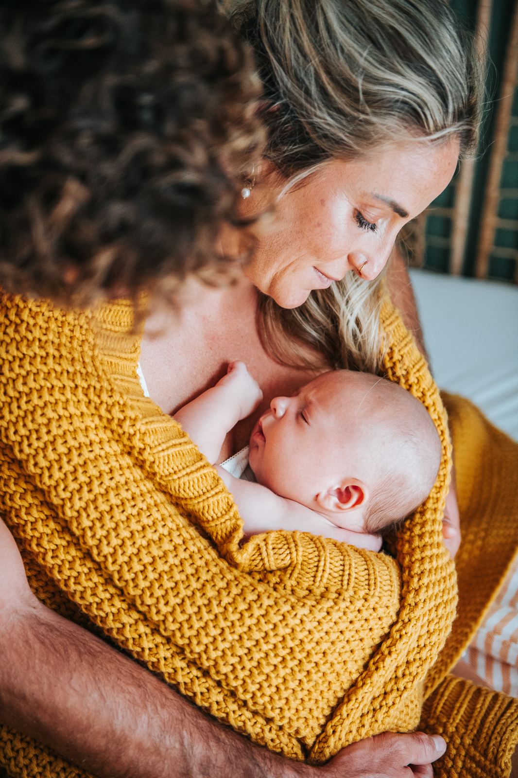 Maman qui serre son bébé dans un plaid jaune
