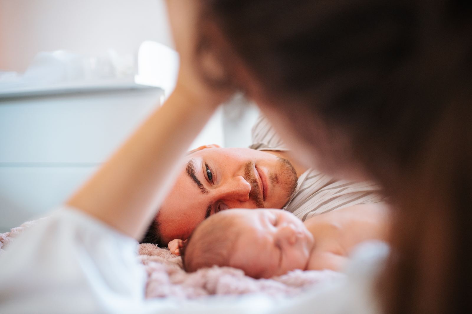 Maman allongée près de son bébé sur le lit, lumière douce