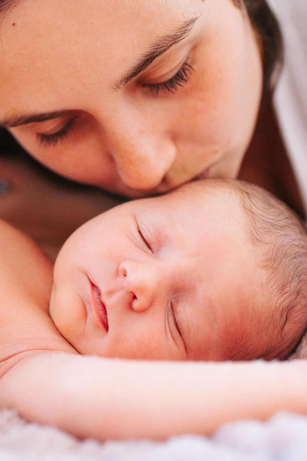 Maman qui embrasse doucement son nouveau-né endormi