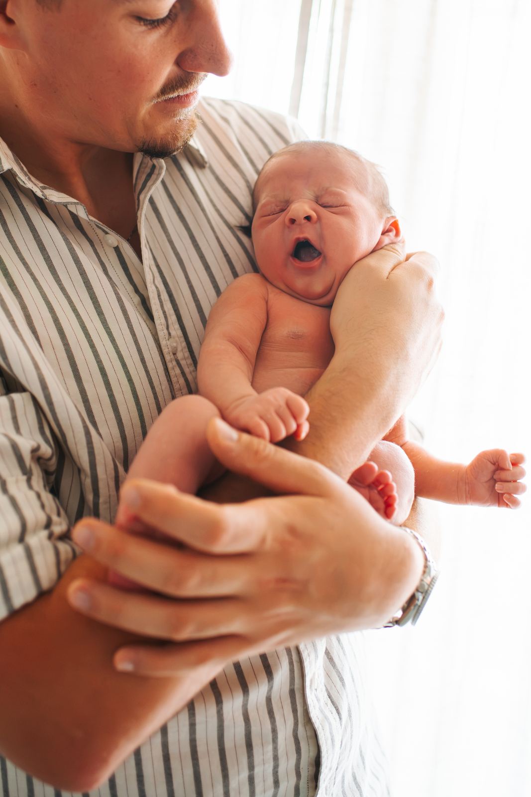 Nouveau-né qui baille dans les bras de son papa