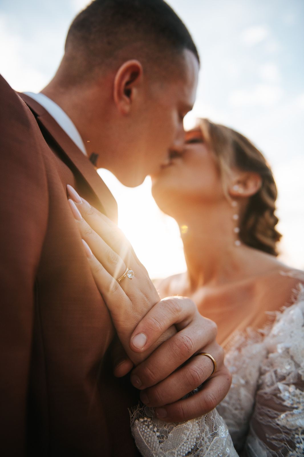 Baiser des mariés en contre-jour au coucher du soleil