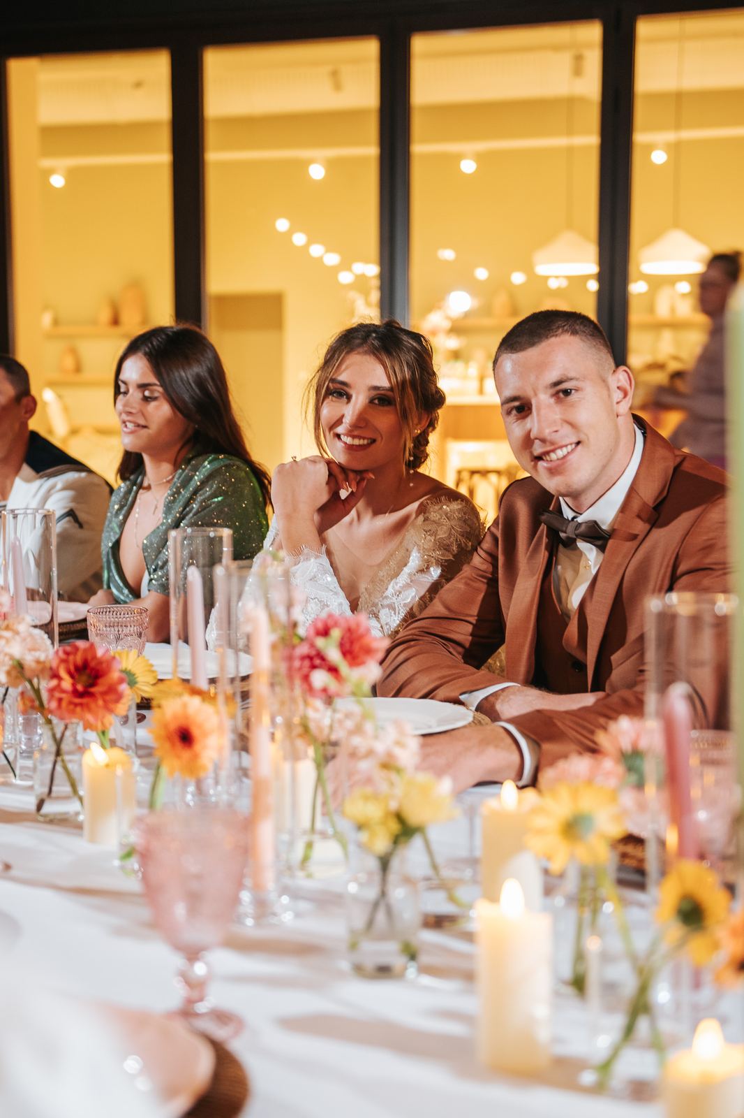 Les mariés à table pendant le dîner, entourés de fleurs et de bougies