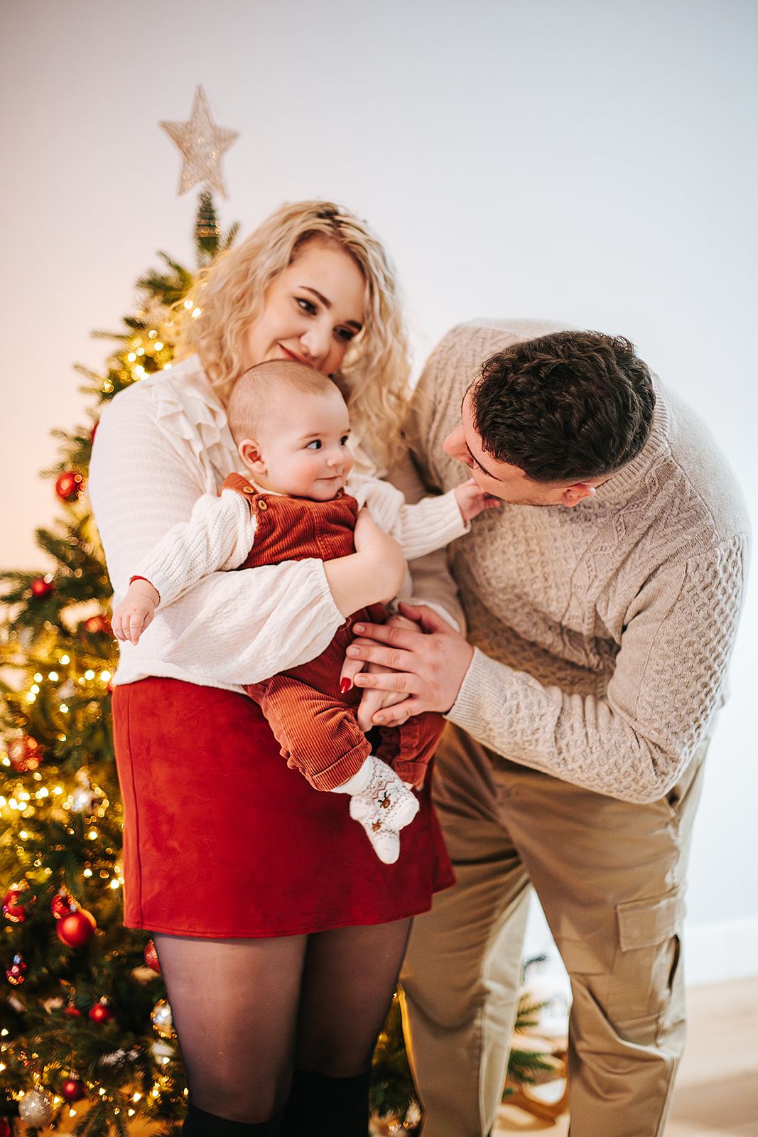 Parents et leur bébé devant le sapin, à la maison