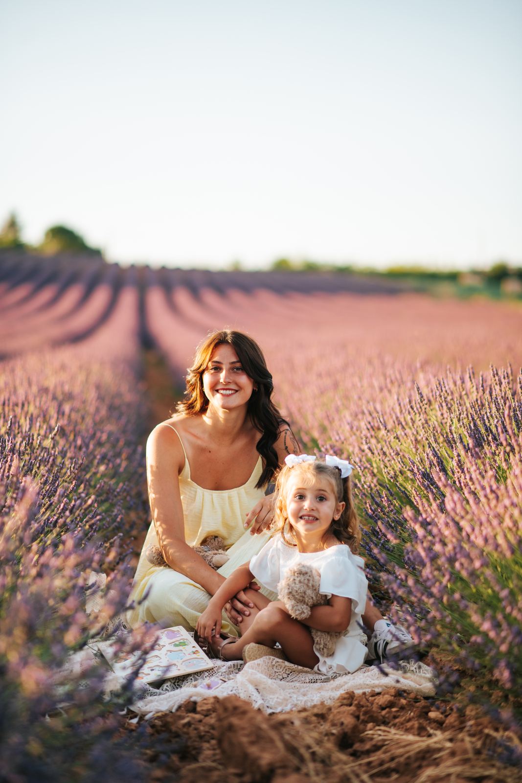 Maman et sa fille assises sur une nappe au milieu de la lavande