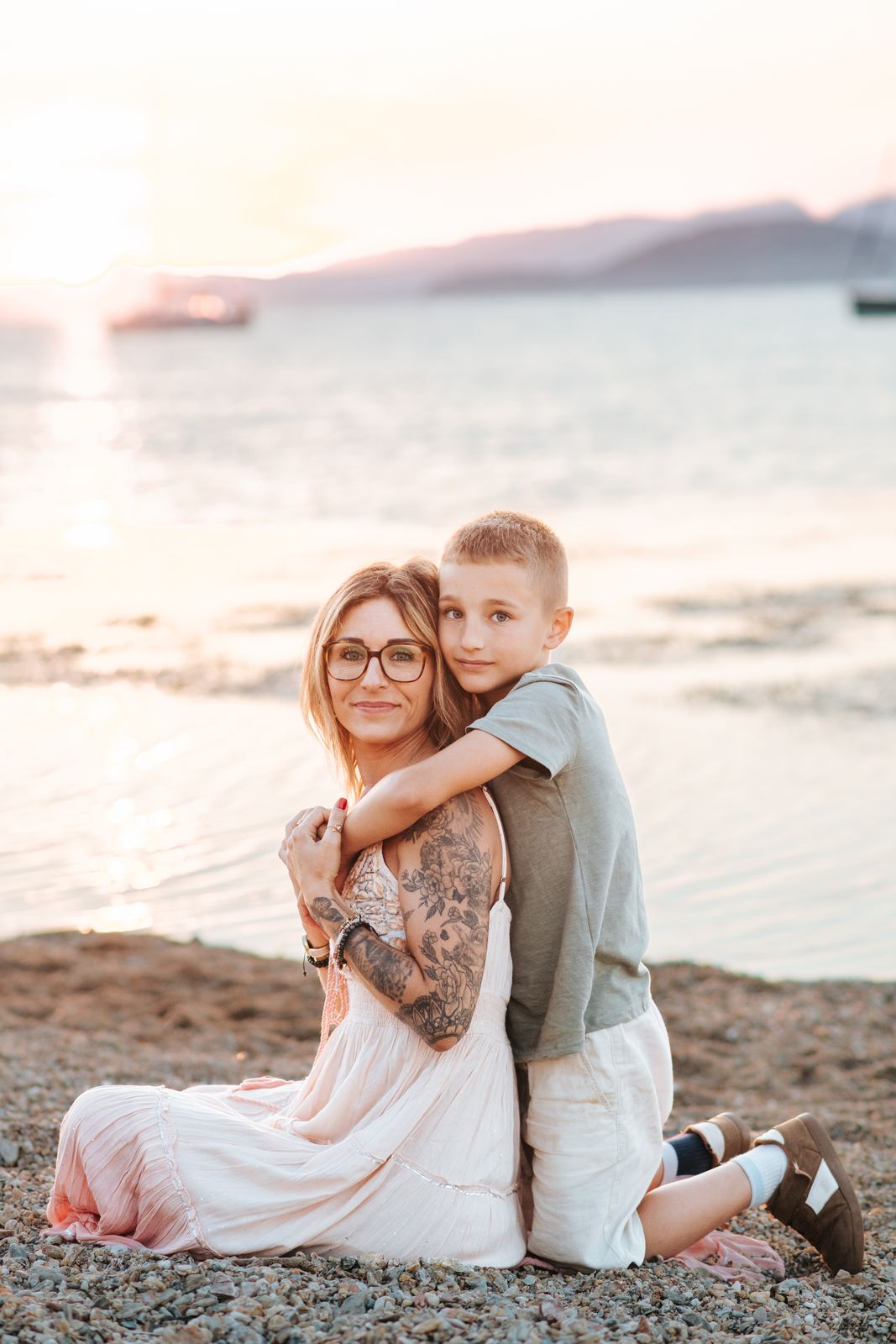 Maman et son fils enlacés sur la plage au coucher du soleil
