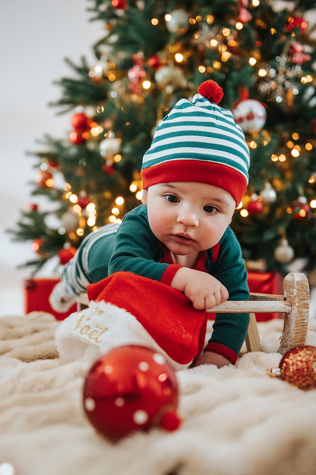 Bébé assis devant le sapin de Noël avec un bonnet
