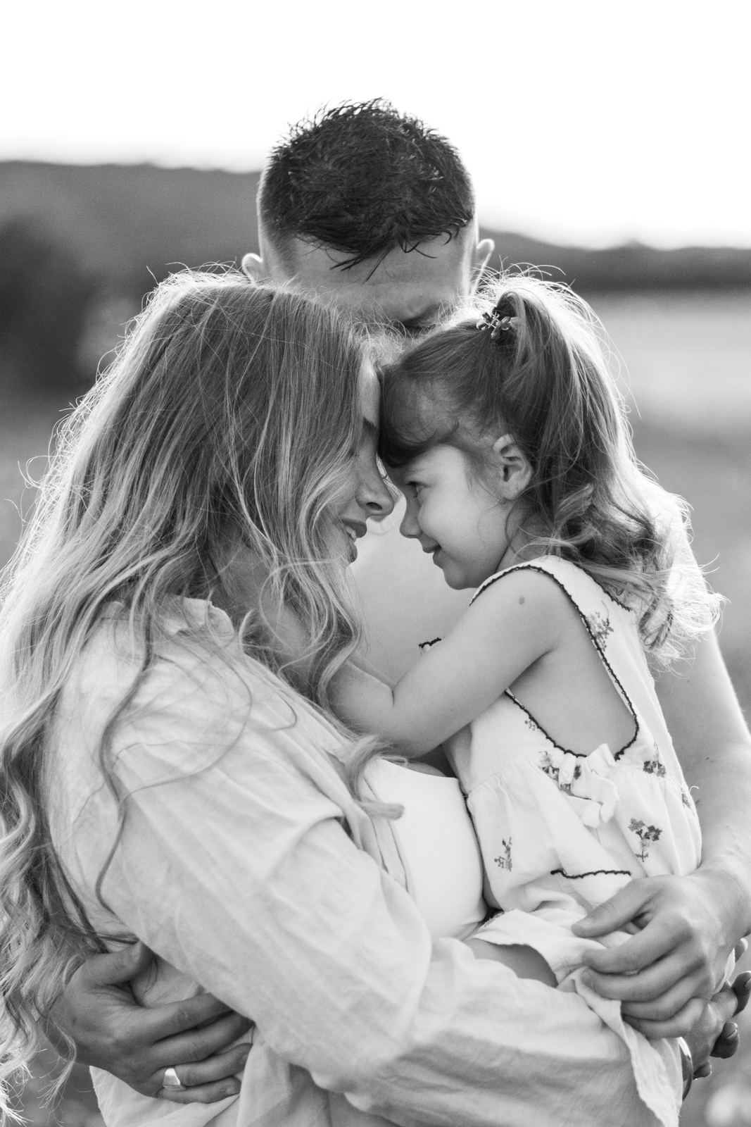 Famille enlacée en noir et blanc pendant une séance grossesse