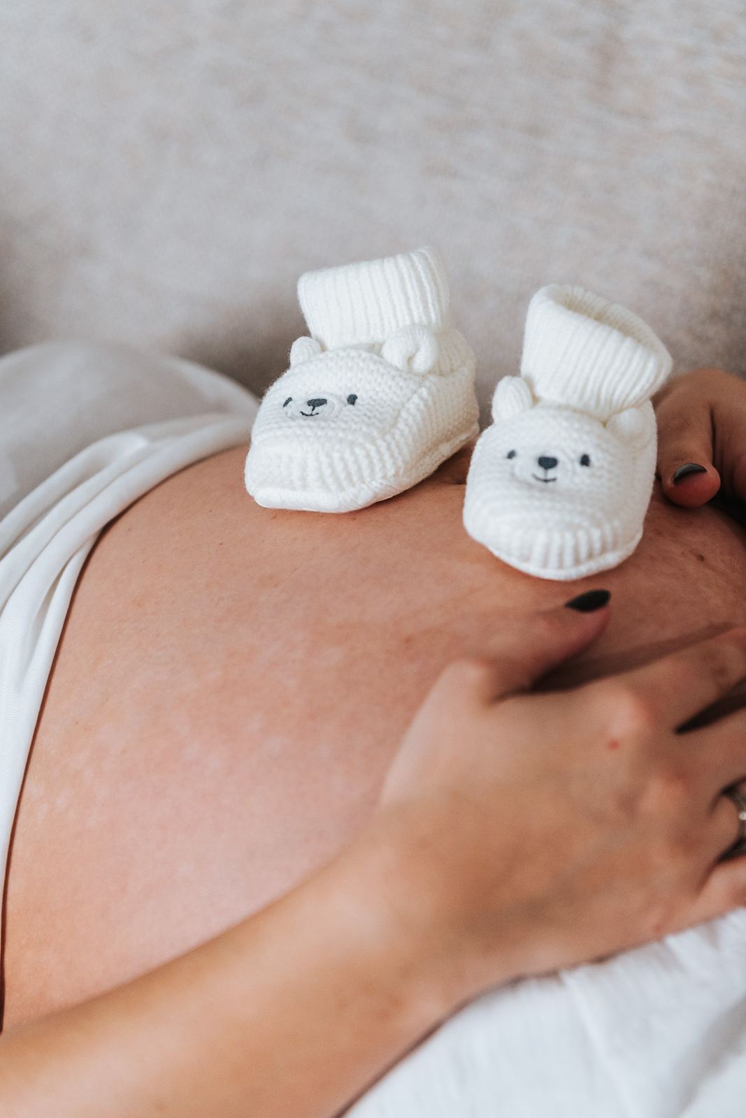 Petits chaussons de bébé posés sur le ventre de grossesse