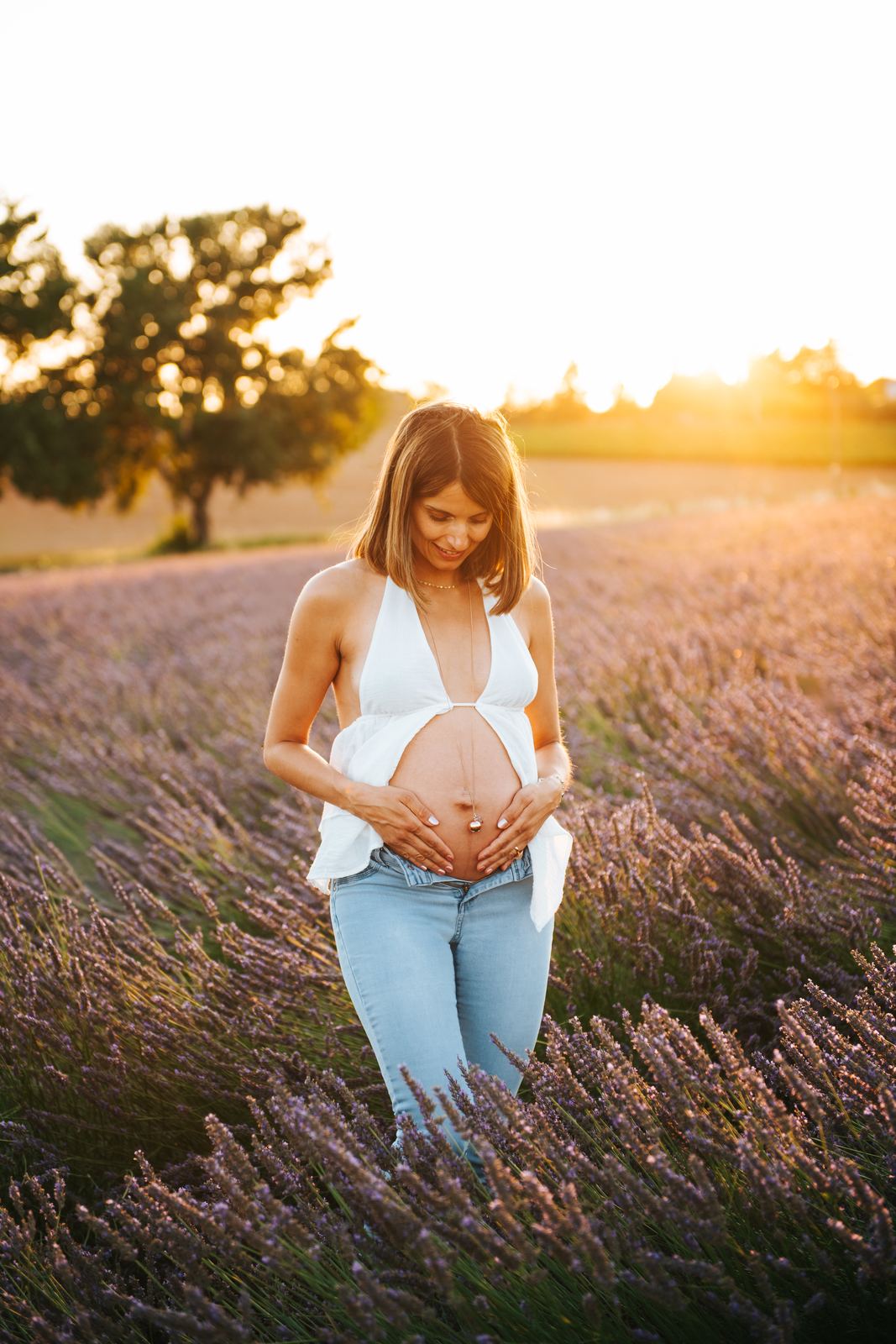 Future maman dans un champ de lavande au coucher du soleil