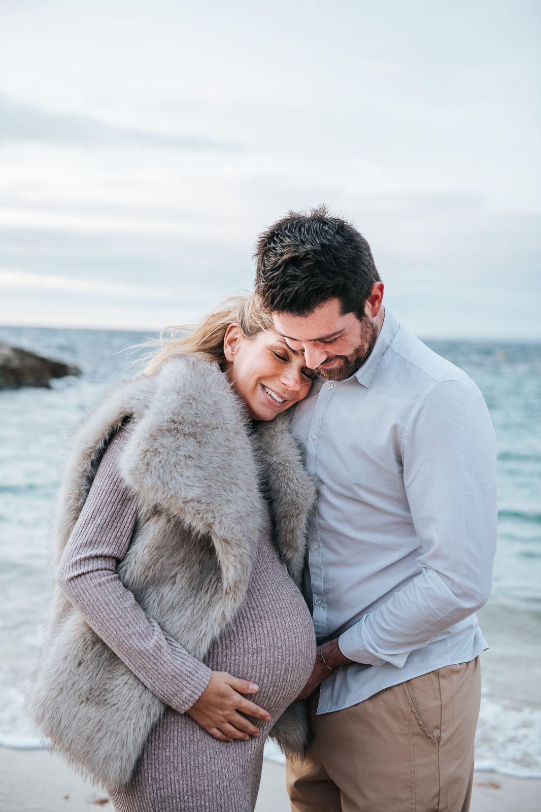 Couple enlacé au bord de la mer sous un ciel gris d'hiver