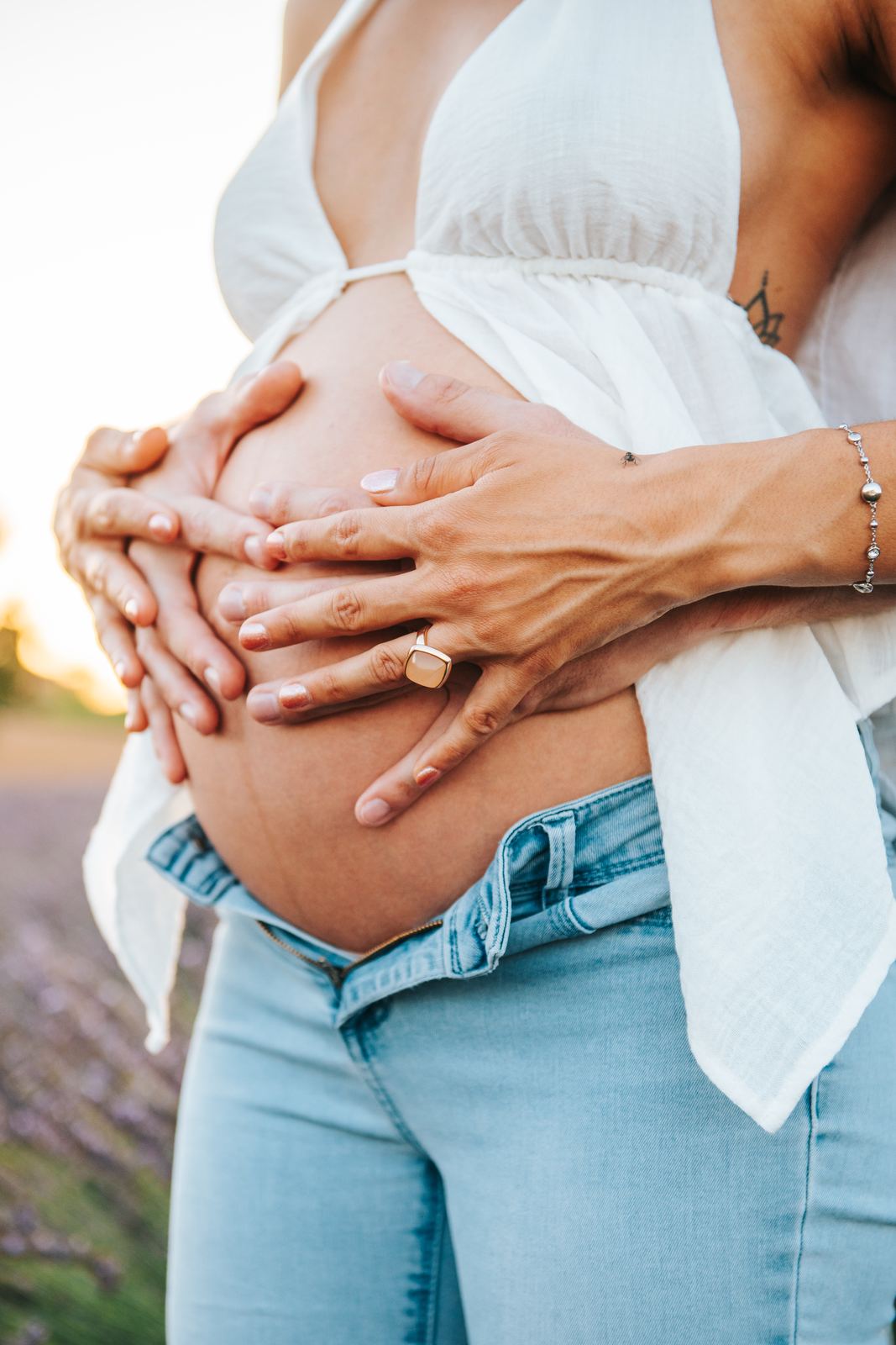 Mains du couple posées sur le ventre de grossesse