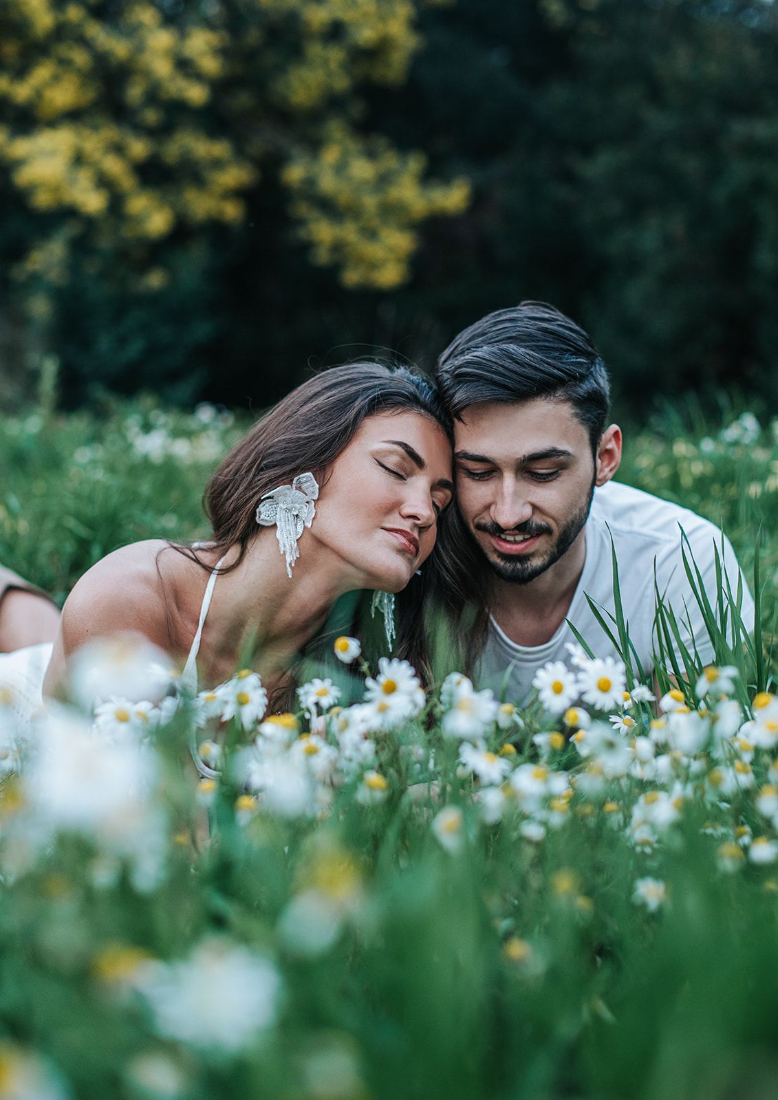 Couple allongé dans les fleurs des champs, joue contre joue