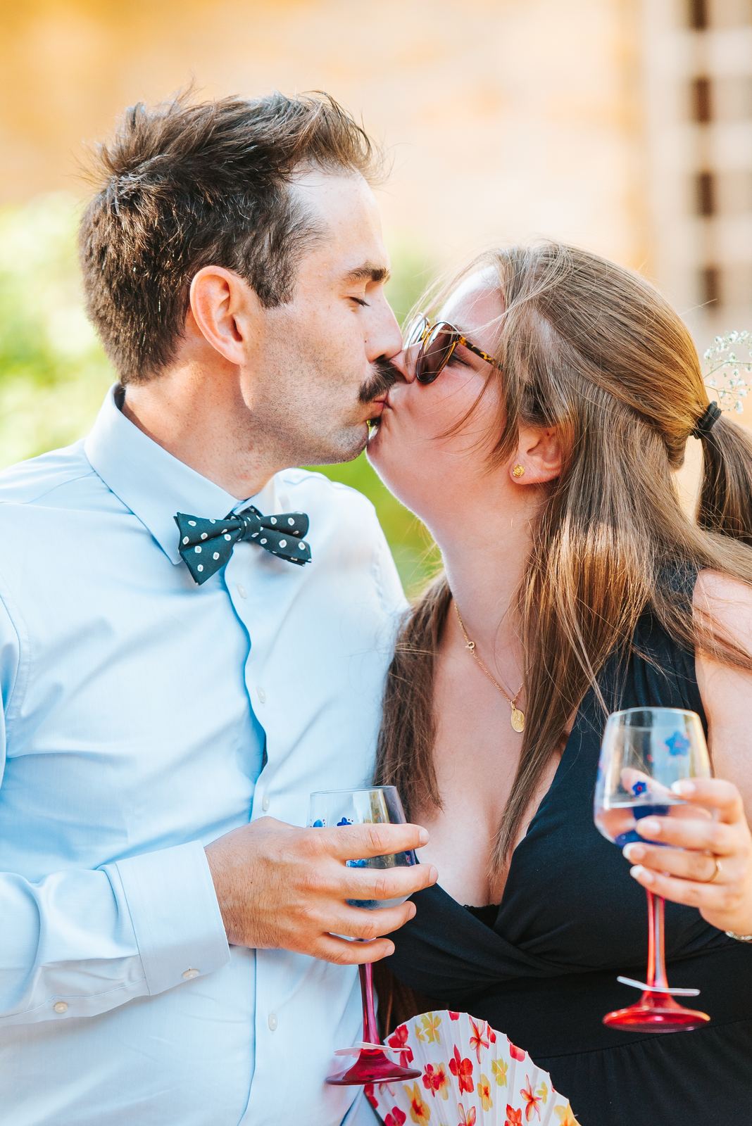 Couple d'invités qui s'embrassent en riant, verre à la main