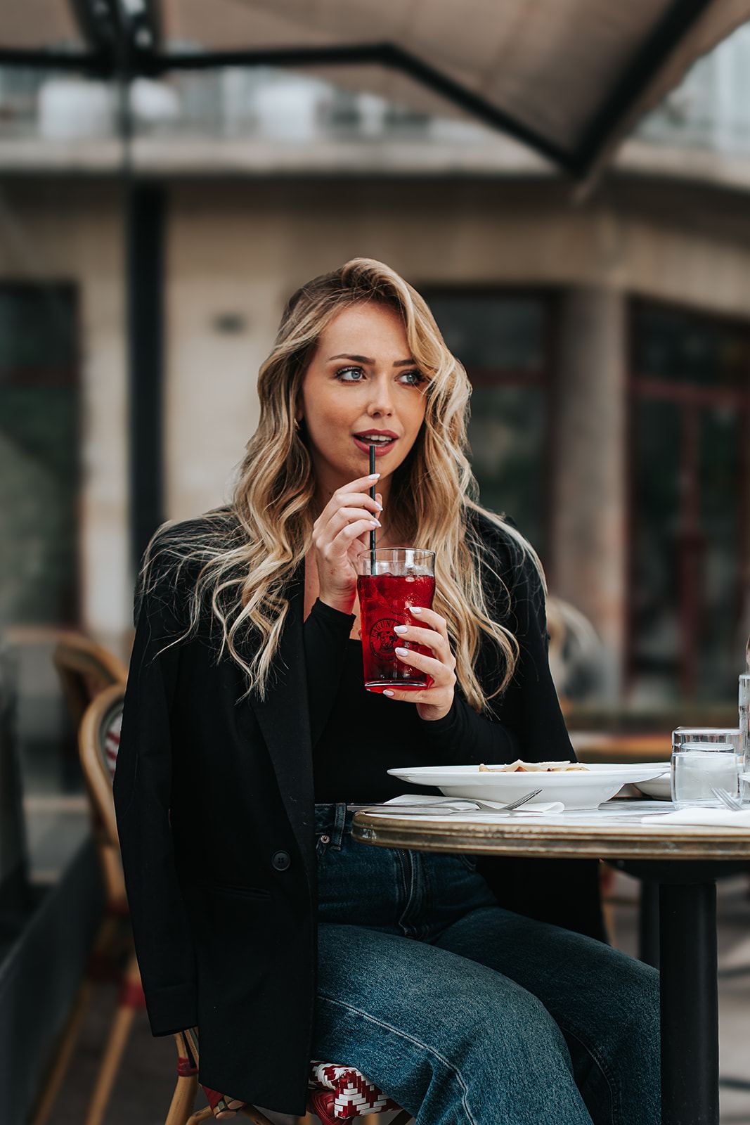 Femme en tenue noire décontractée à la terrasse d'un café