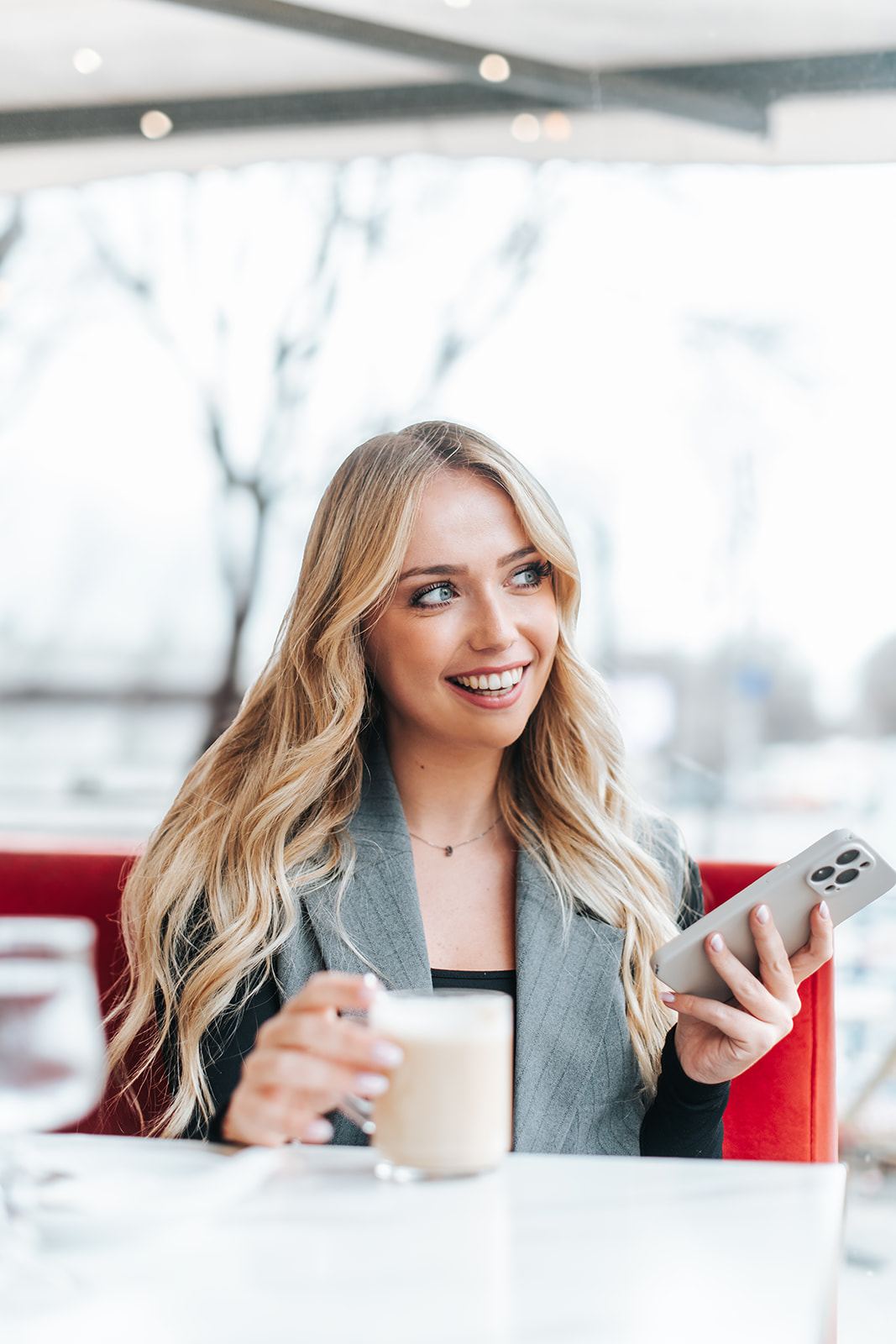 Femme souriante à la terrasse d'un café à Marseille, téléphone à la main