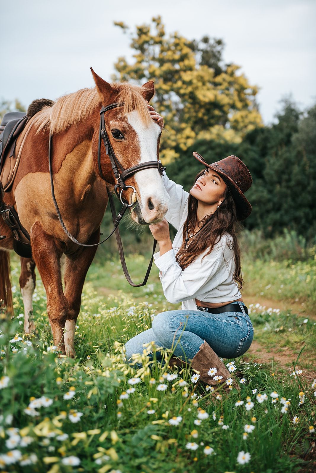 Femme accroupie près de son cheval, dans les fleurs