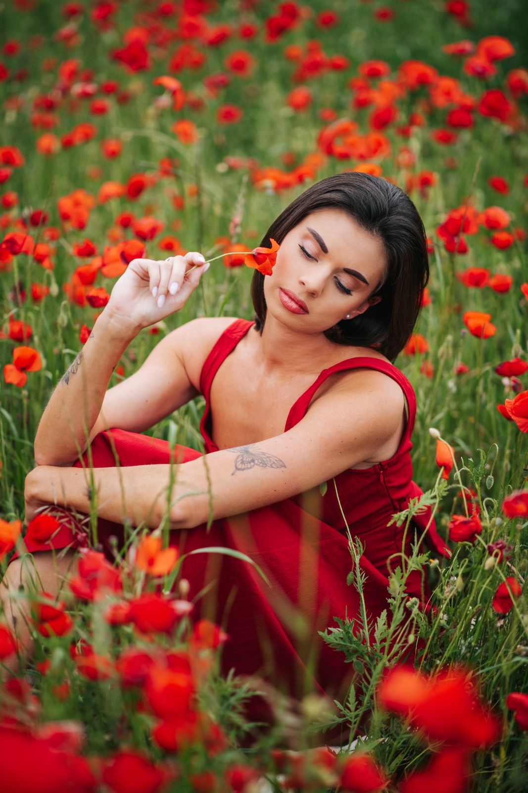 Portrait en robe rouge assise dans les coquelicots