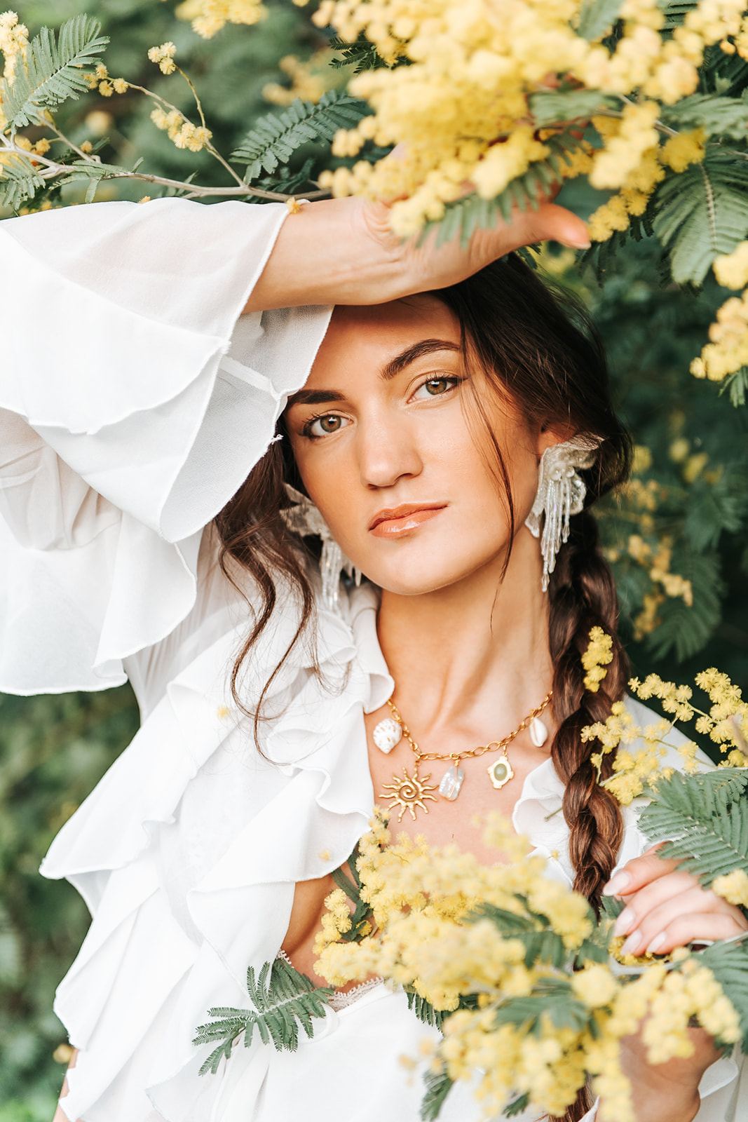 Femme coiffée d'une tresse, des brins de mimosa dans les mains