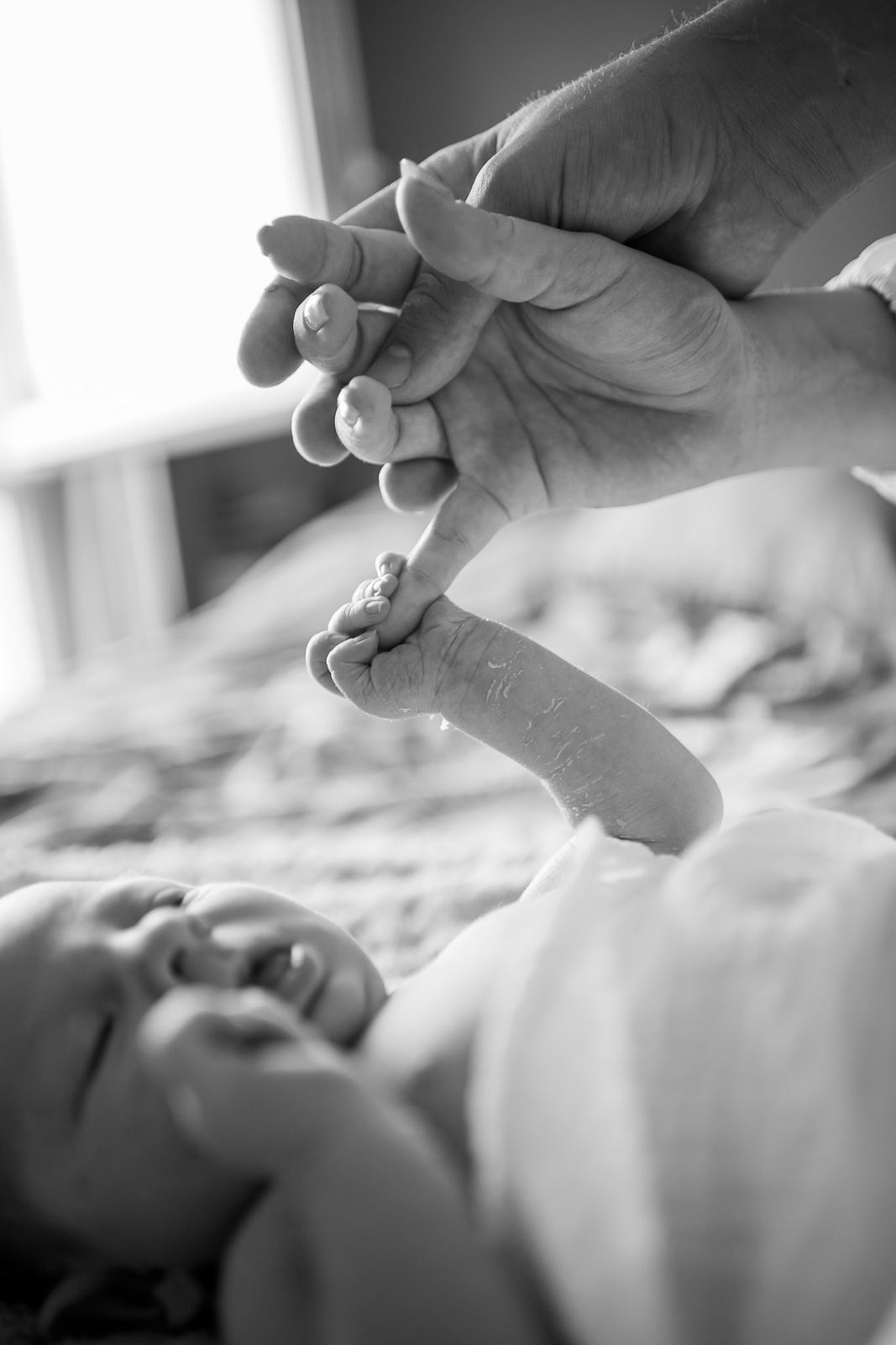 Main d'un parent au-dessus de son bébé endormi, en noir et blanc