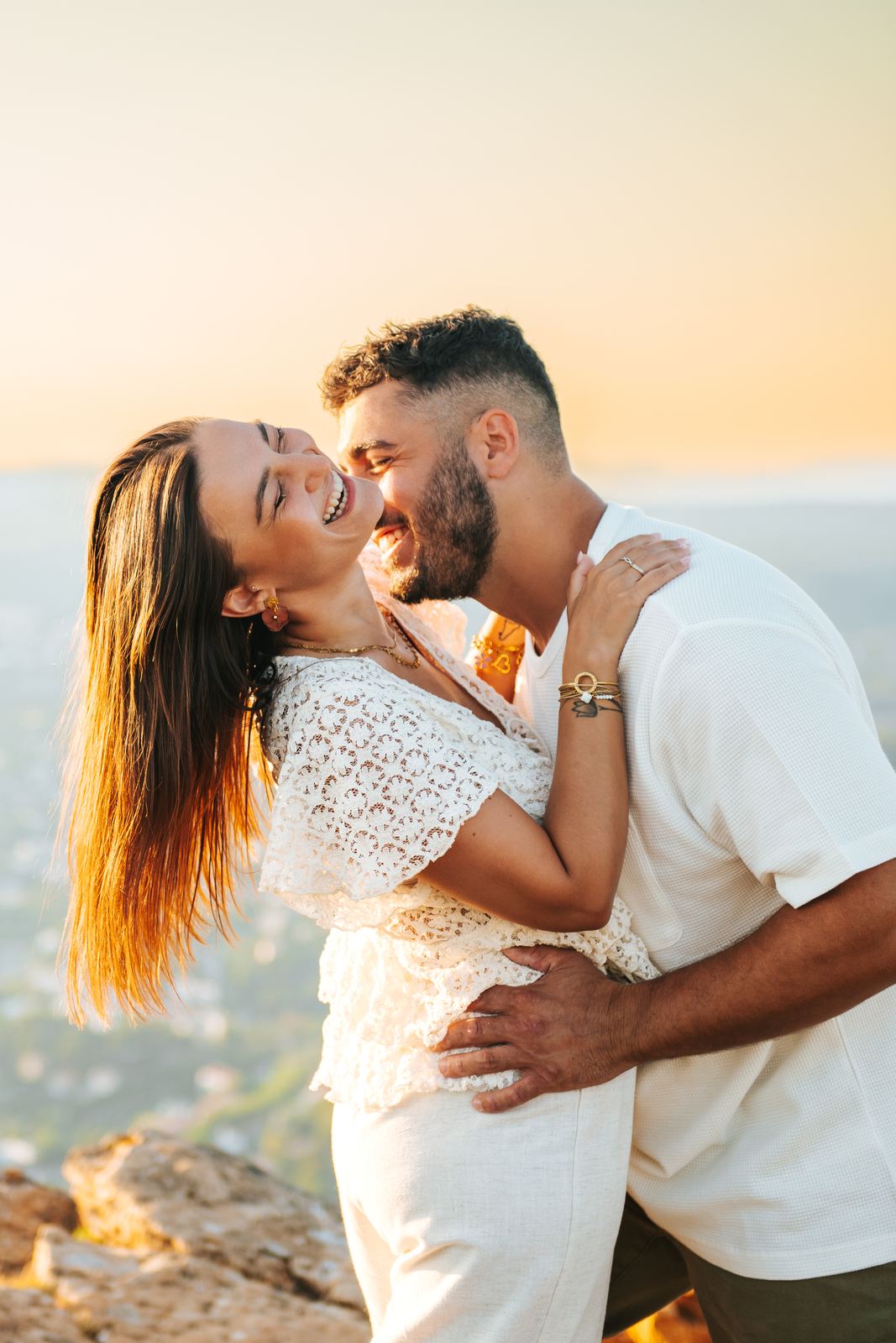 Couple qui rit, ses cheveux à elle soulevés par le vent