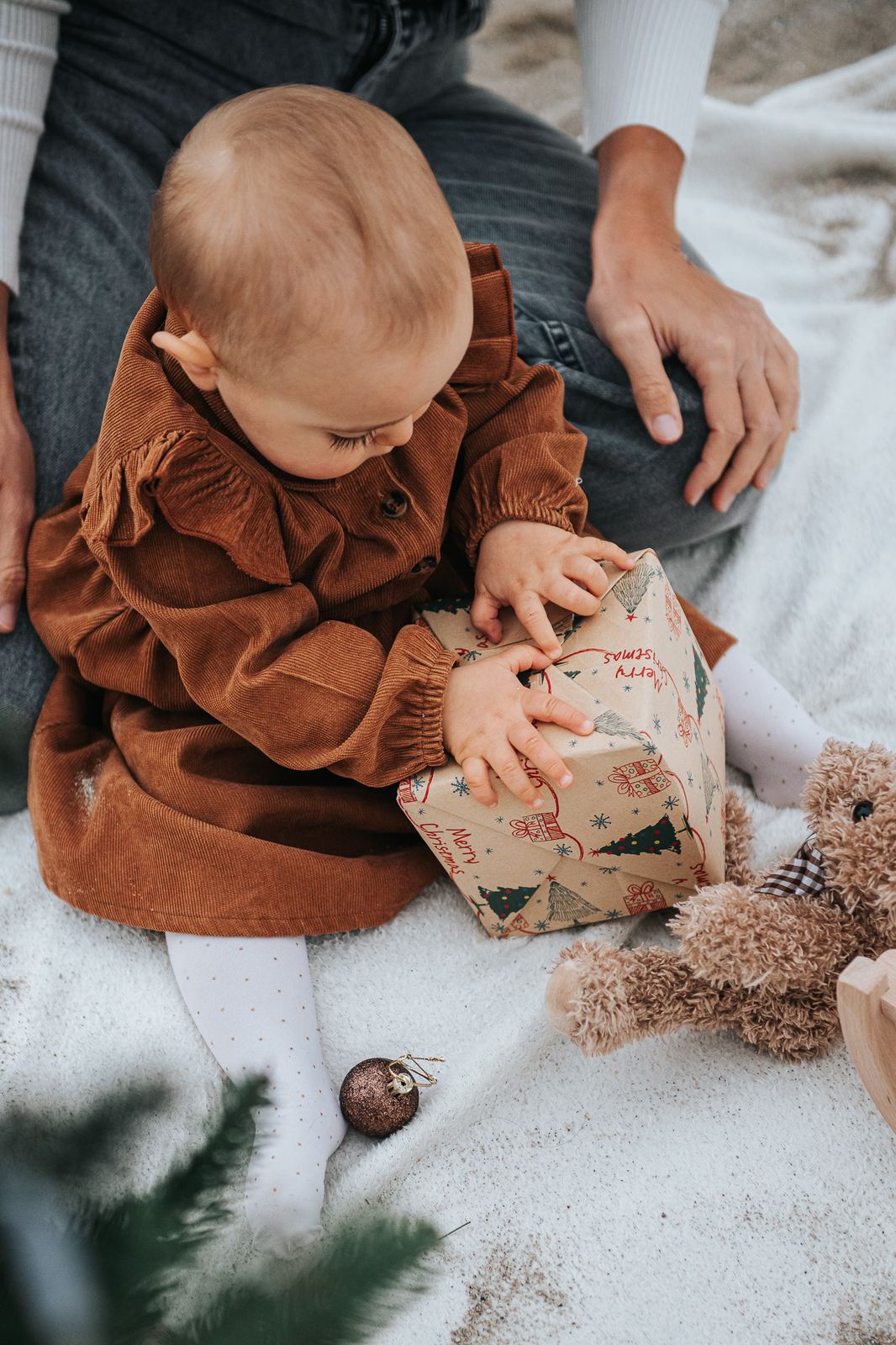 Bébé qui ouvre un petit paquet cadeau sur une couverture