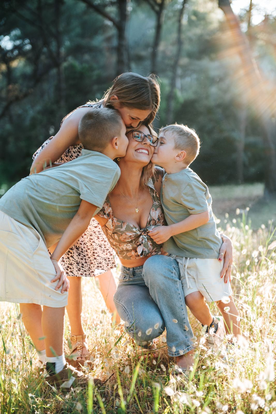 Trois enfants qui couvrent leur maman de bisous