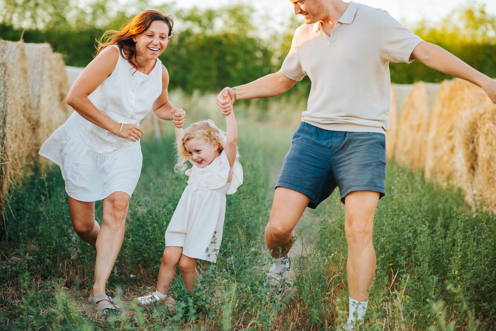 Parents qui courent en tenant leur fille par la main dans l'herbe