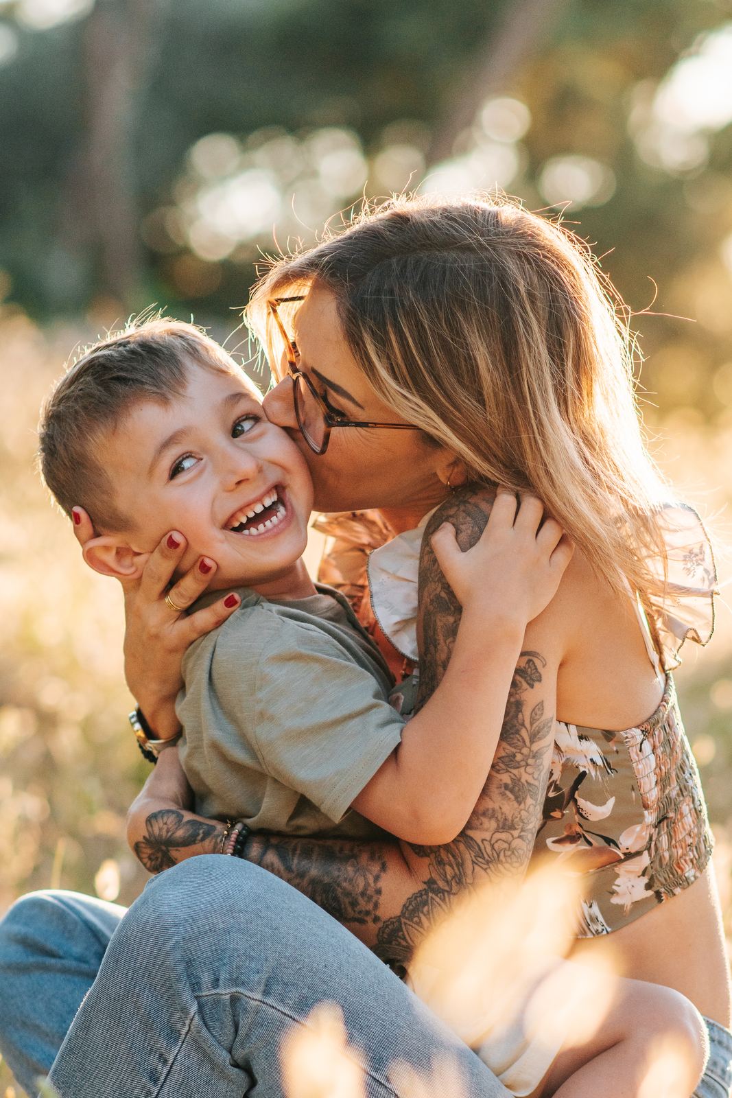 Petit garçon qui éclate de rire pendant que sa maman l'embrasse