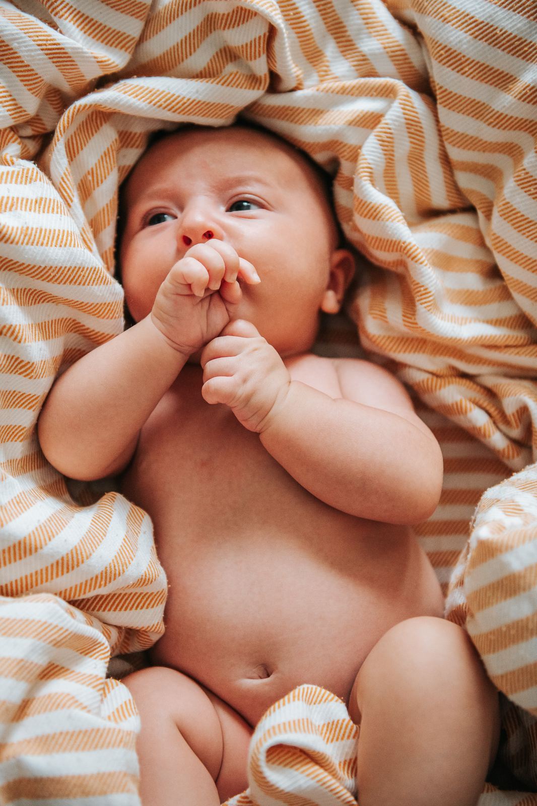 Bébé éveillé allongé sur un drap rayé
