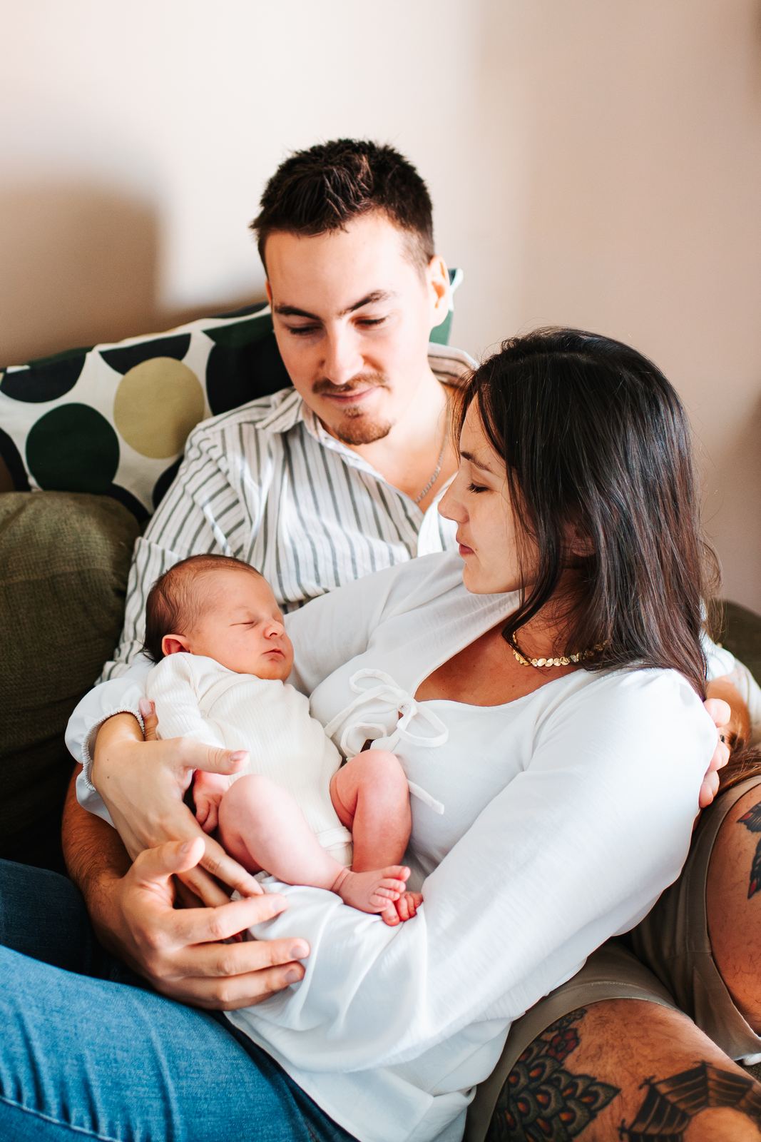 Jeunes parents sur leur canapé avec leur nouveau-né dans les bras