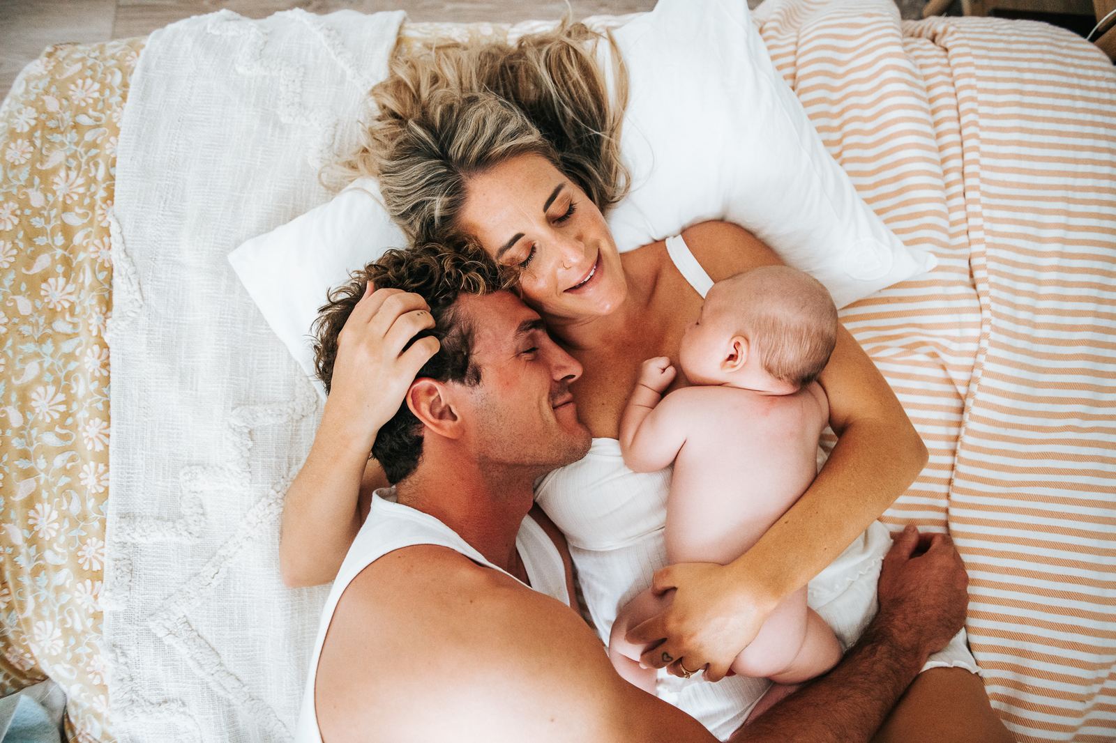 Jeunes parents allongés sur leur lit avec leur nouveau-né