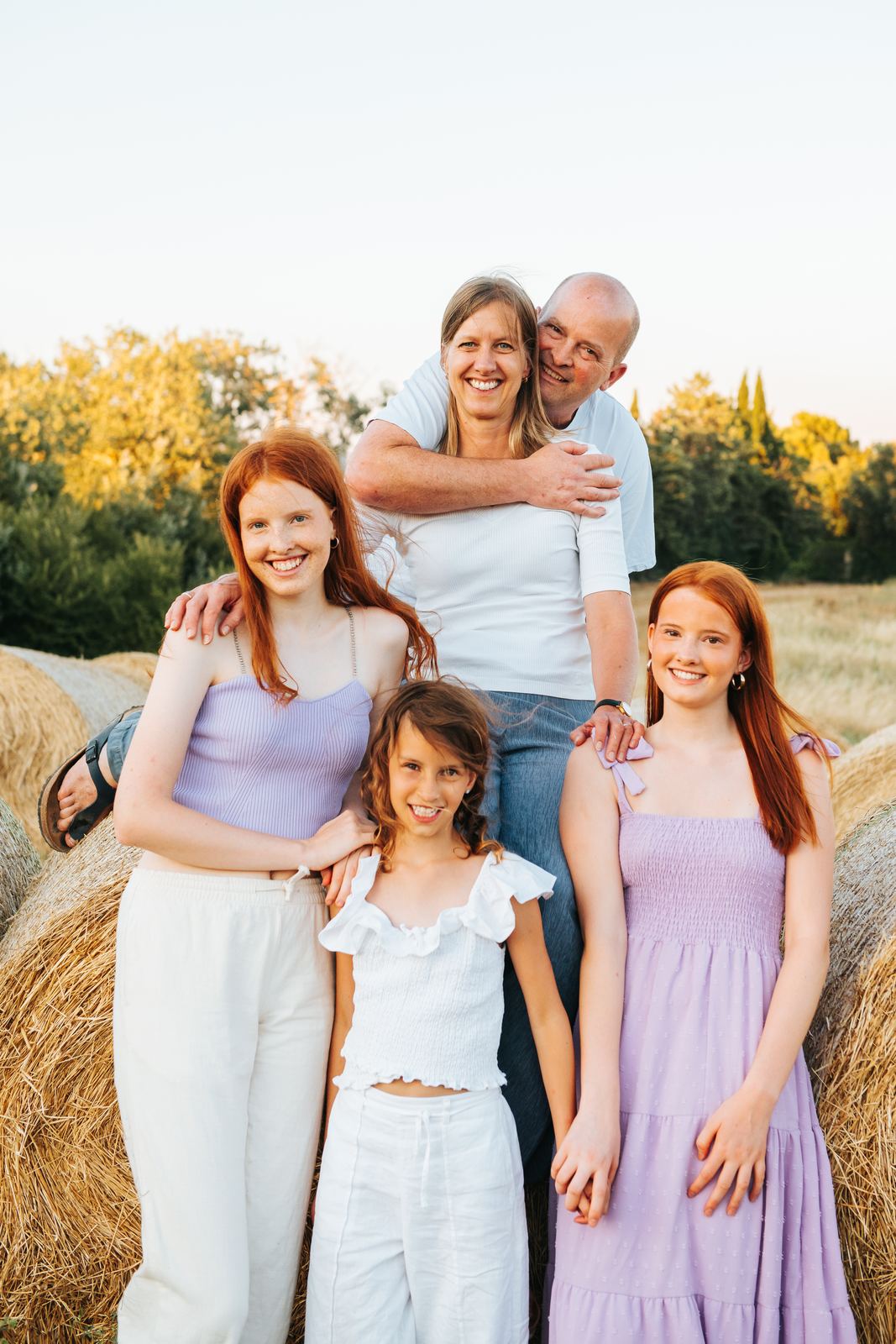 Famille réunie devant des bottes de paille en tenues claires et lilas