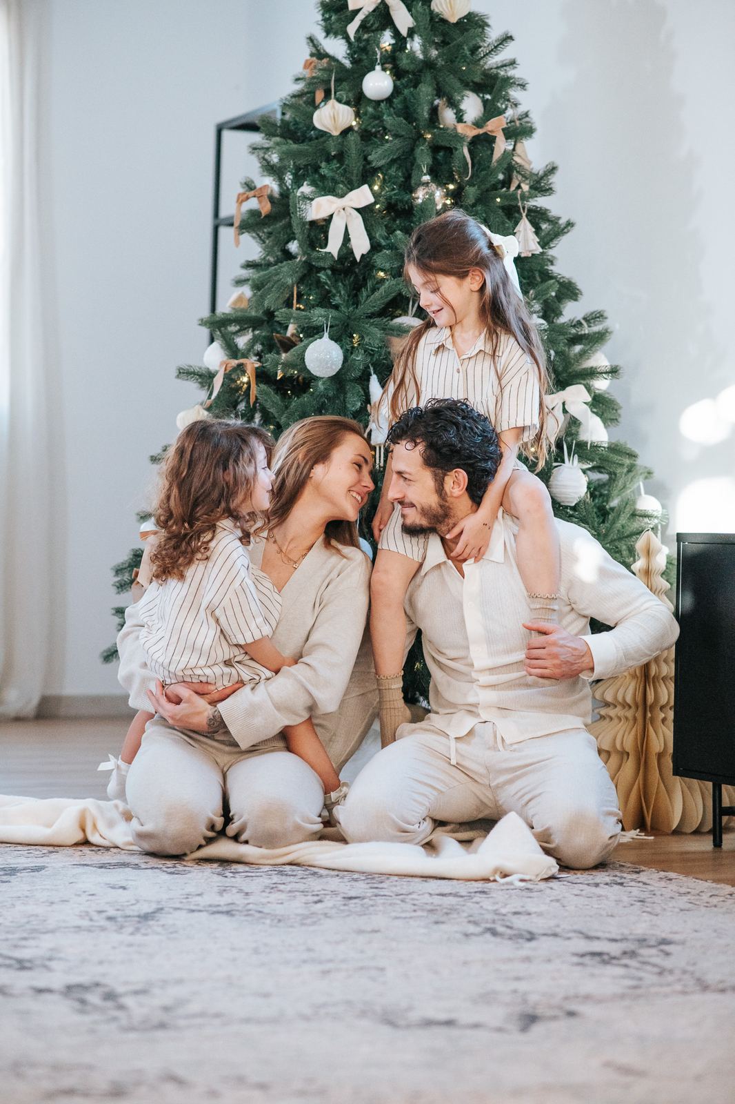 Famille en tenues crème et beige assise devant le sapin