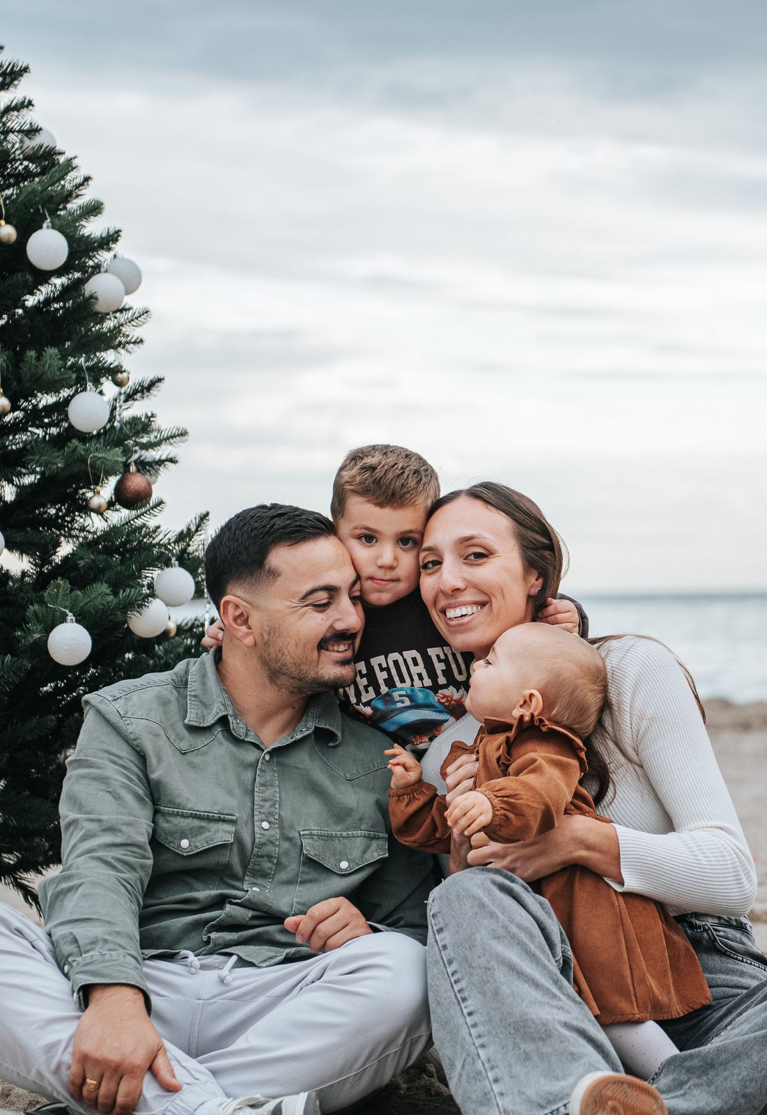 Famille en tenues vert, brun et crème sur la plage en hiver