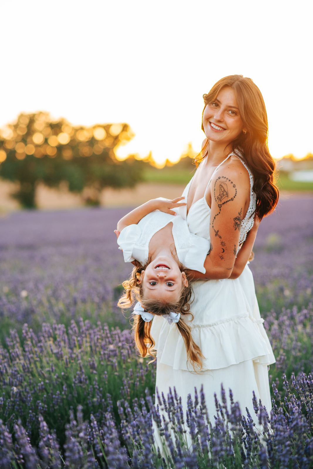 Maman en robe fluide qui fait rire sa fille dans la lavande