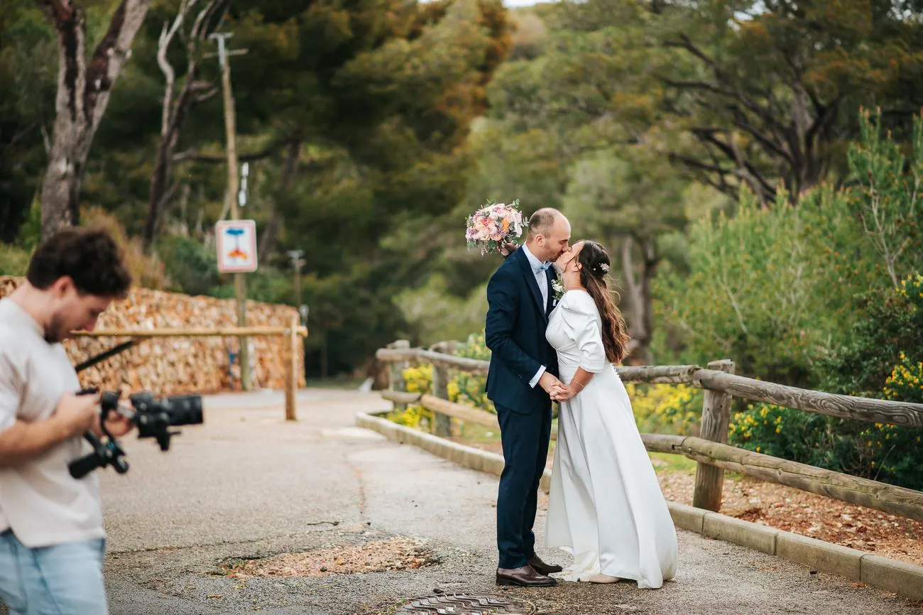 Coulisses d'un mariage : Thomas filme les mariés qui s'embrassent sur un chemin bordé de pins