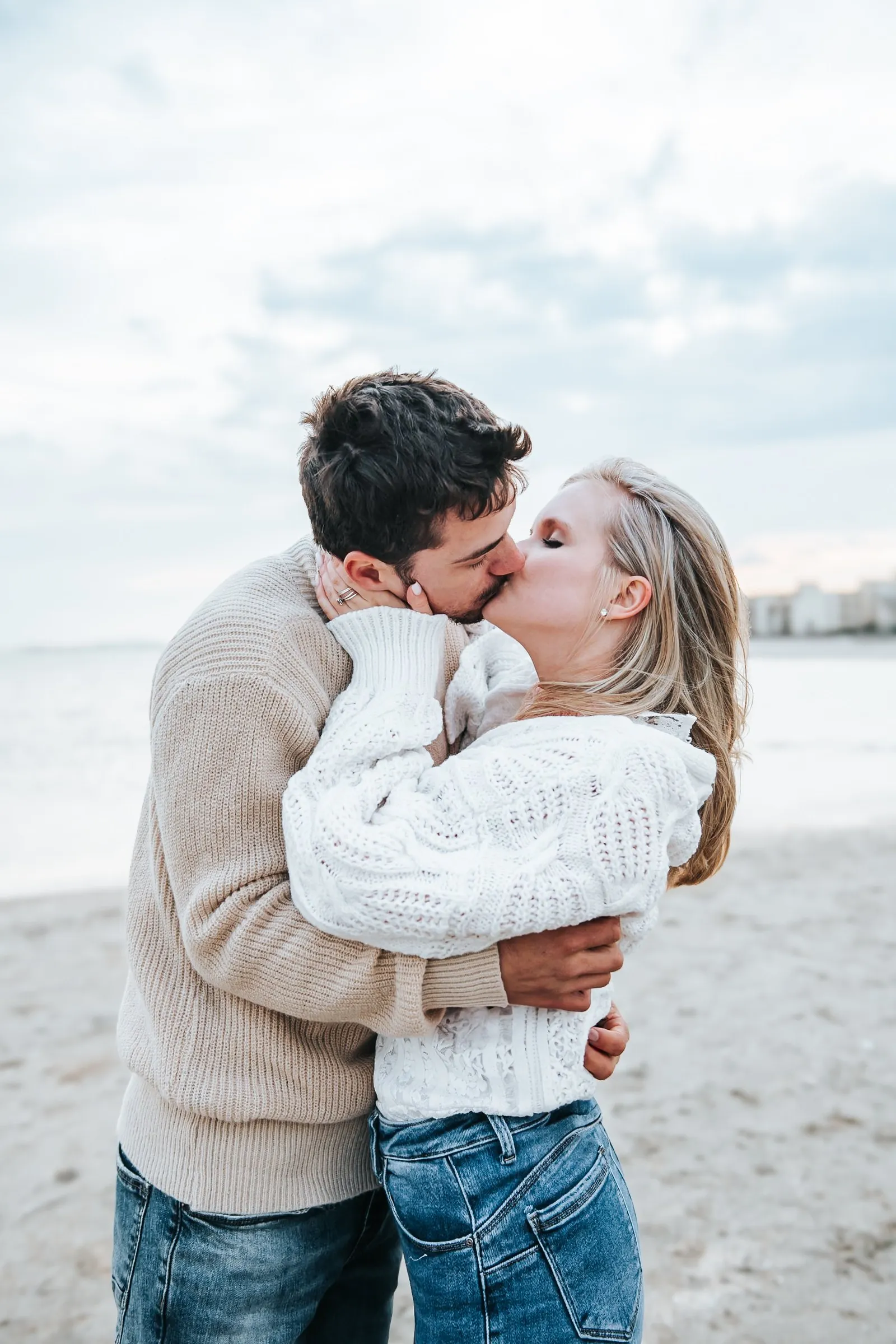 Séance couple sur la plage près de Montpellier : ils se regardent en souriant, la mer derrière eux