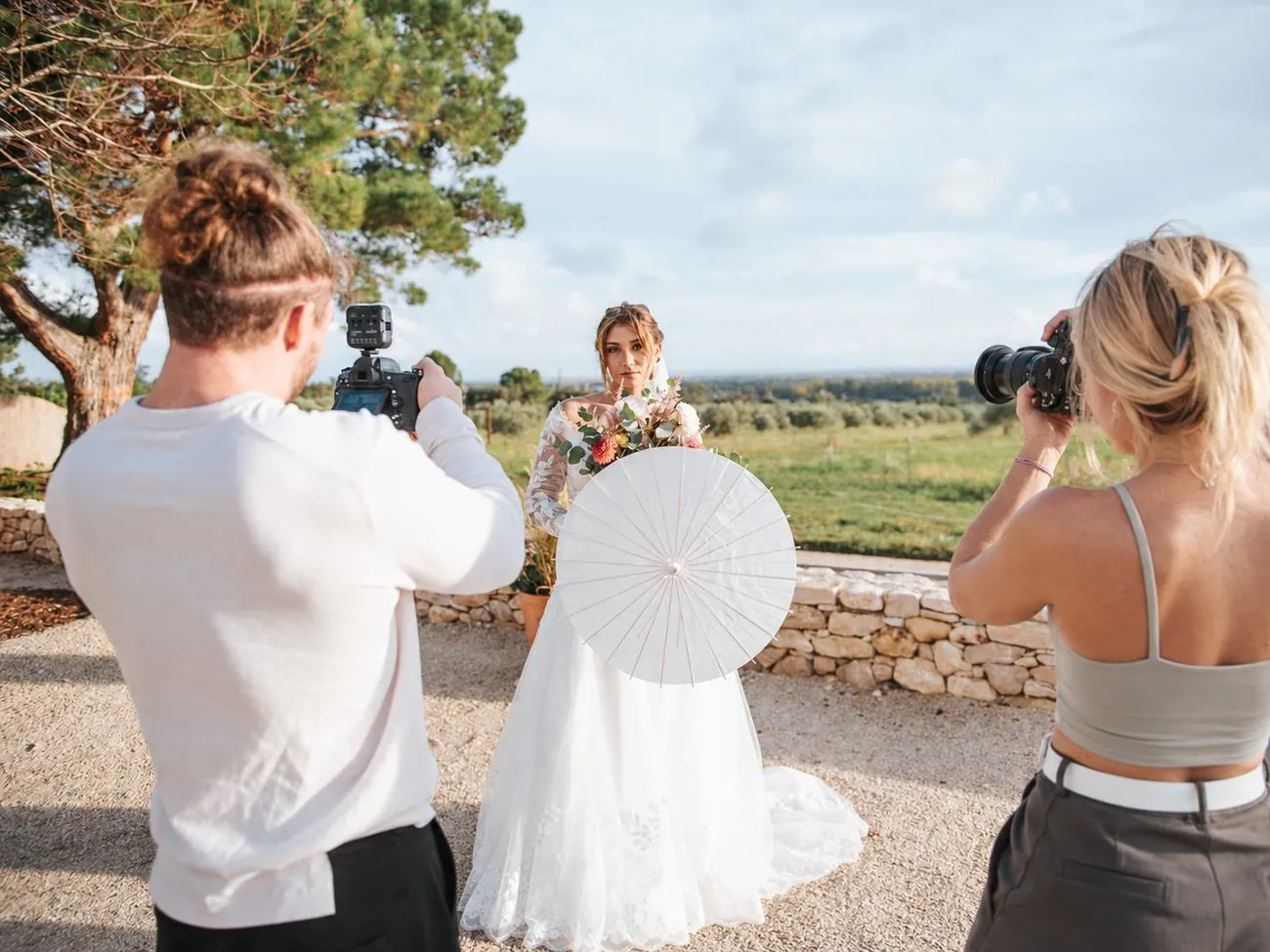 Léna photographie et Thomas filme une mariée aux ombrelles