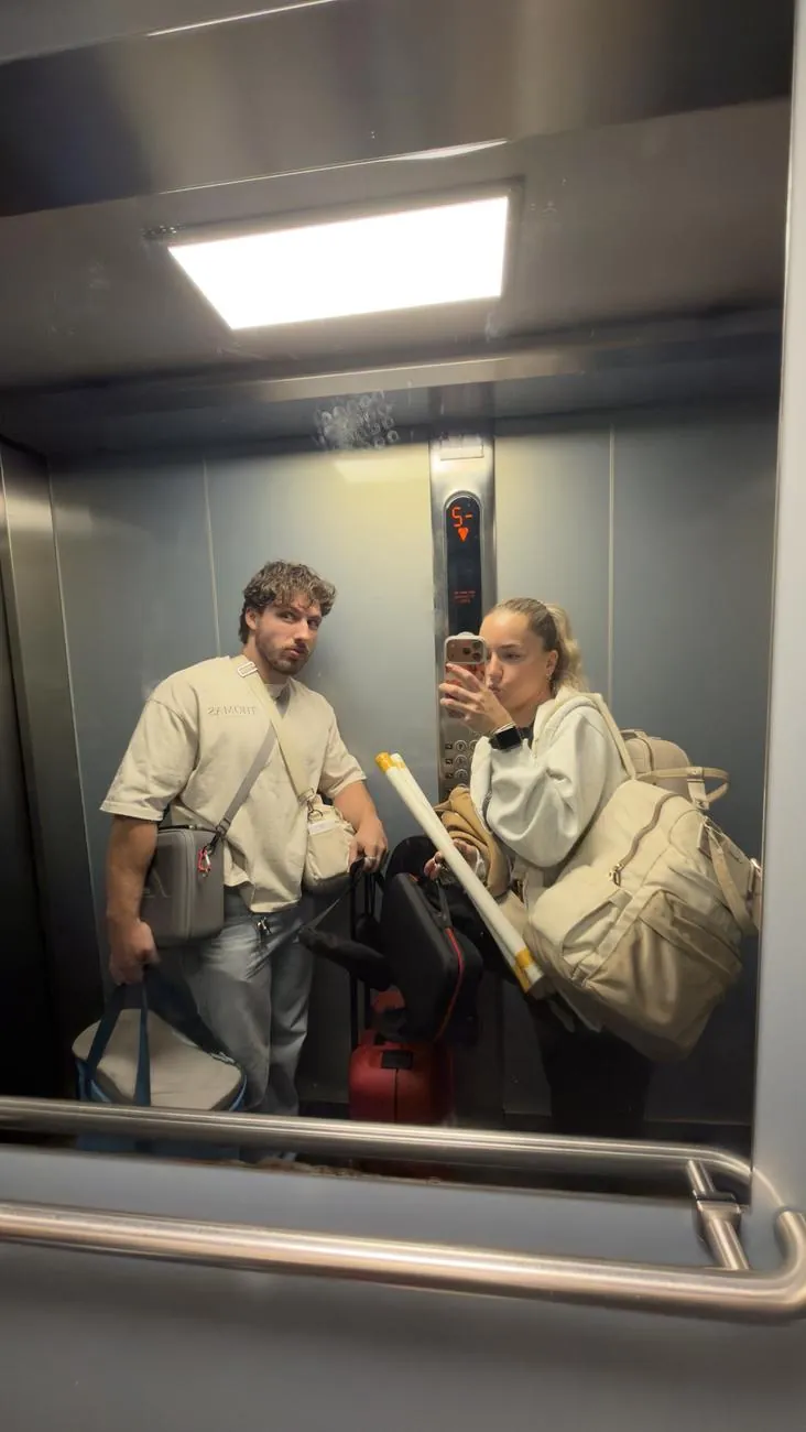 Léna et Thomas dans le miroir de l'ascenseur, chargés de matériel