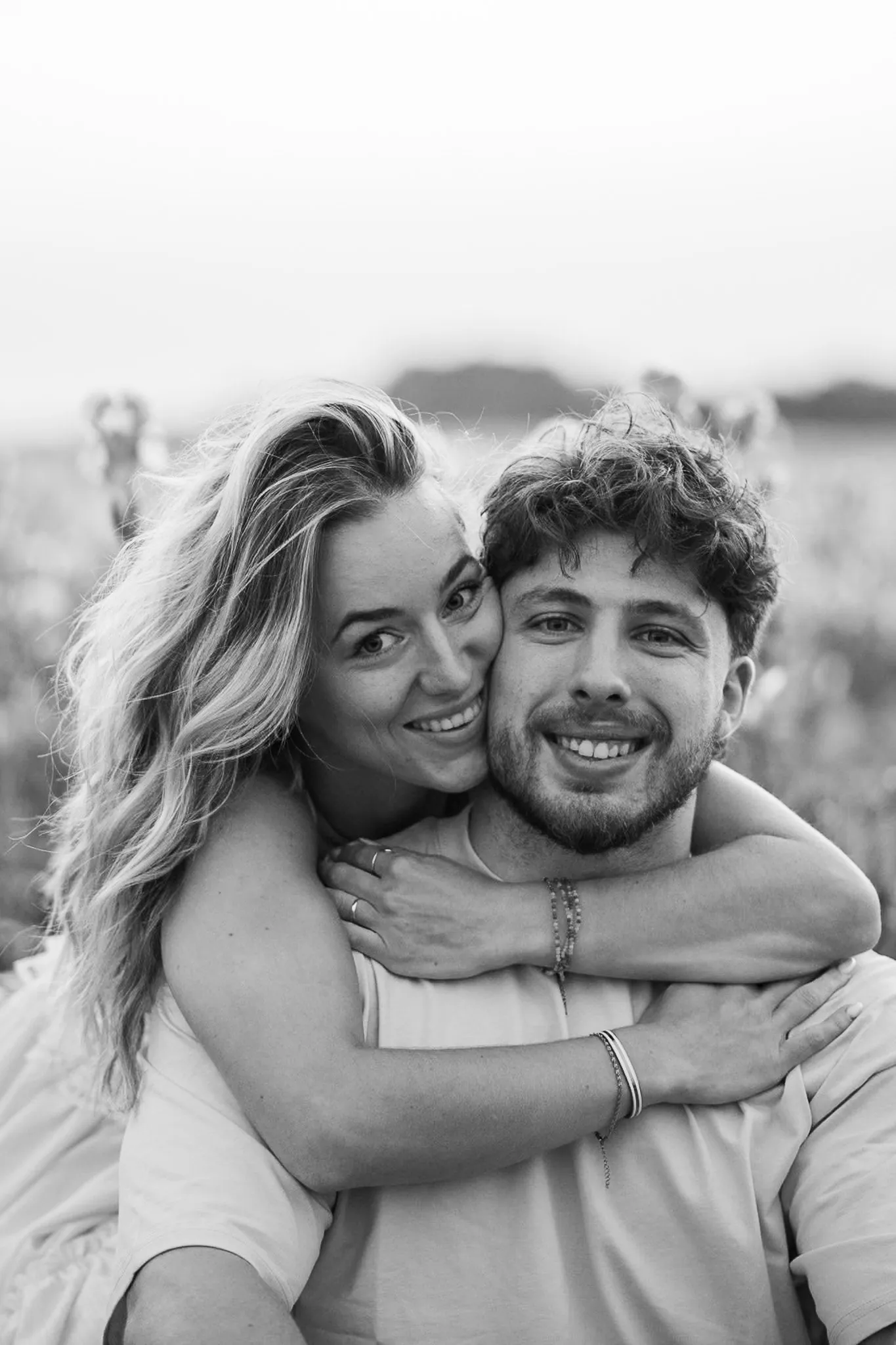 Léna et Thomas en noir et blanc, joue contre joue, elle l'enlace par derrière, grands sourires