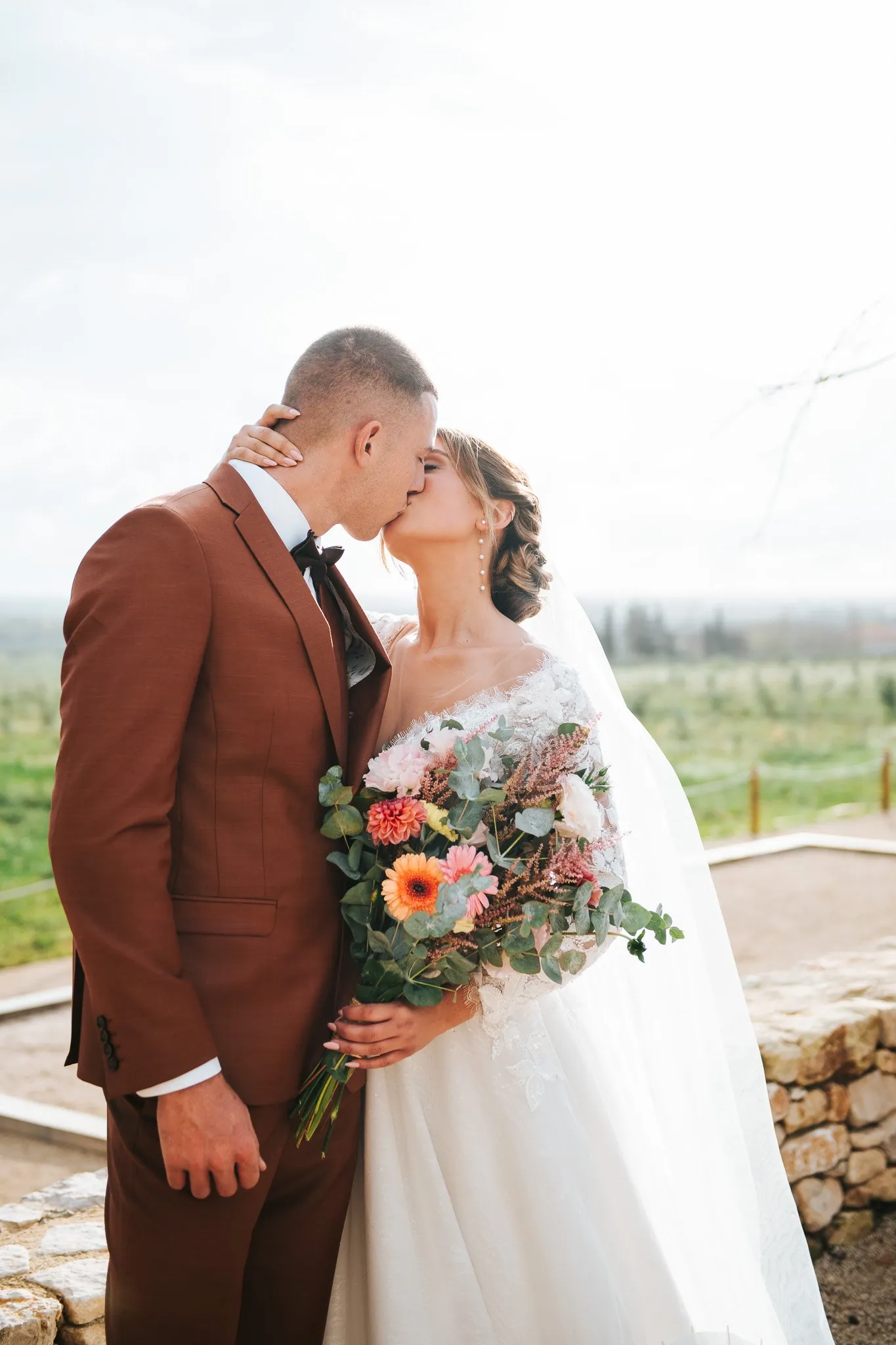 Les mariés enlacés avec le bouquet, dans la lumière du soir des Alpilles