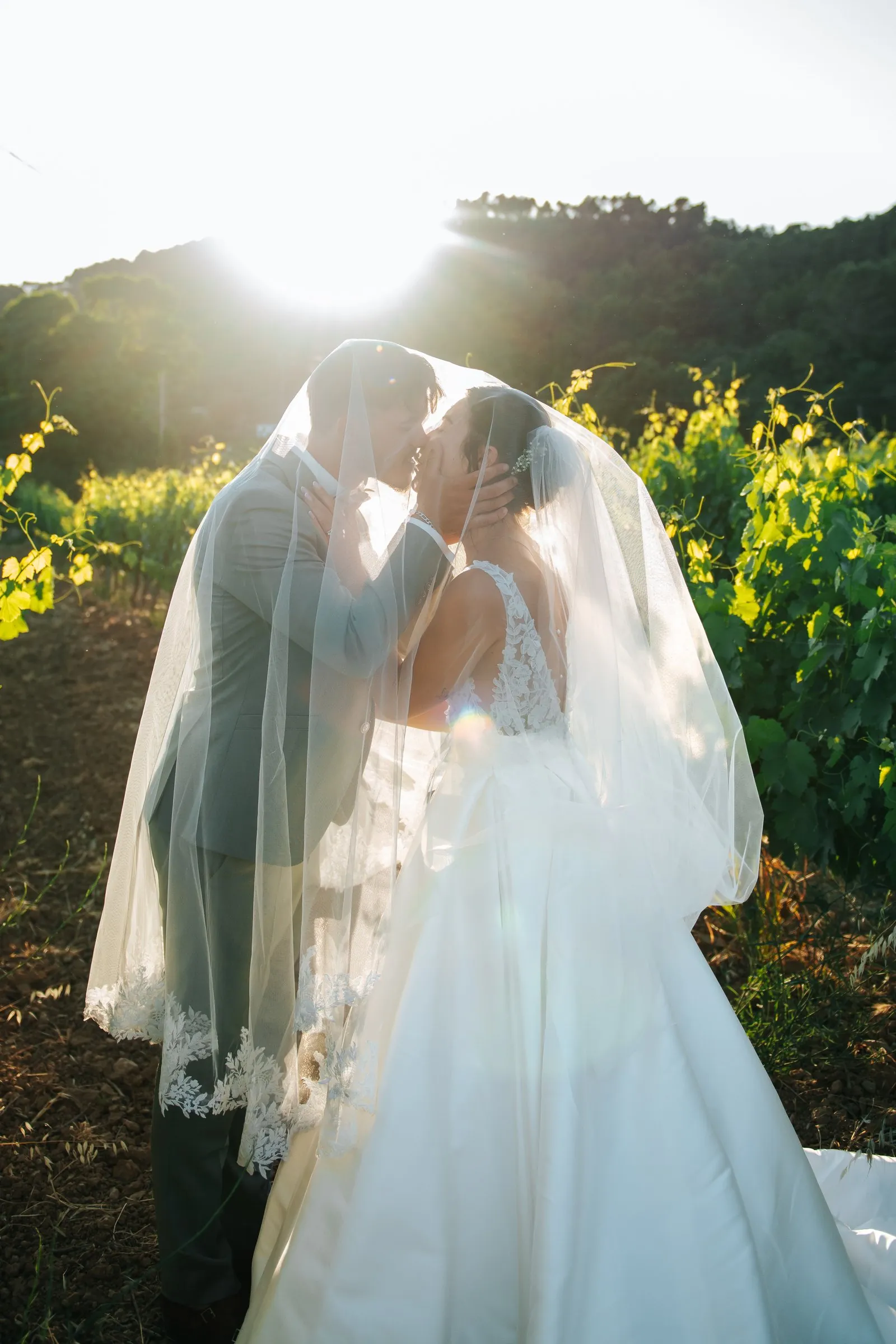 Mariage : baiser passionné des mariés, mains de la mariée posées sur le costume gris clair du marié