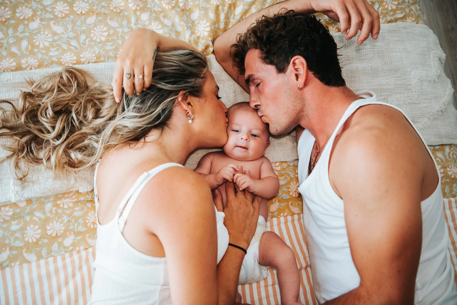 Parents qui embrassent leur bébé dans leur lit