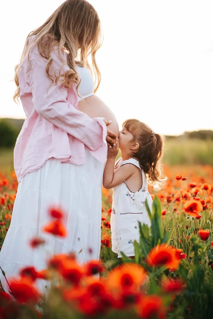 Petite fille qui embrasse le ventre de sa maman dans les coquelicots