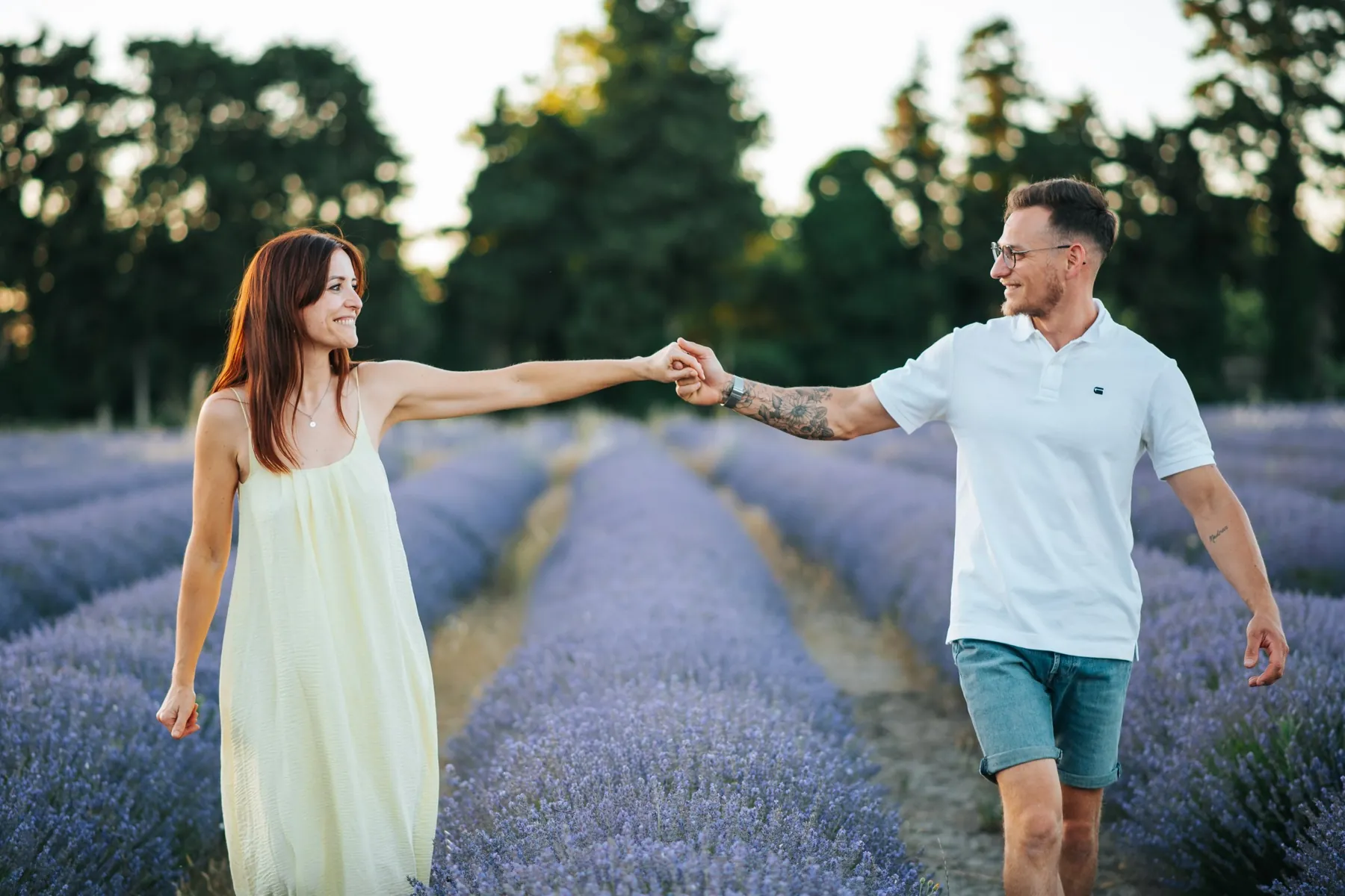 Le couple marche main dans la main entre les rangs de lavande