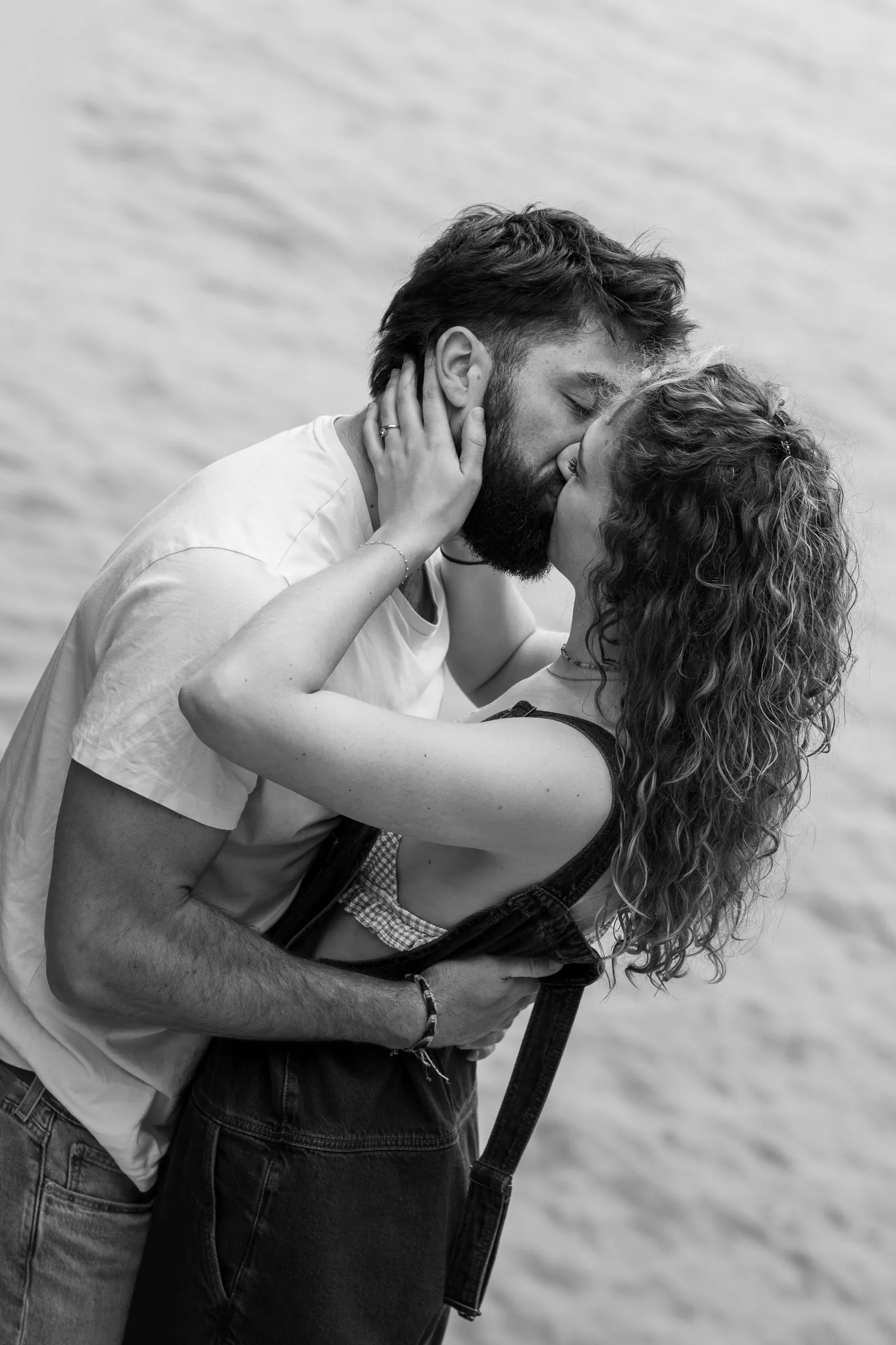 Séance fiançailles sur la plage : un baiser au bord de l'eau, en noir et blanc