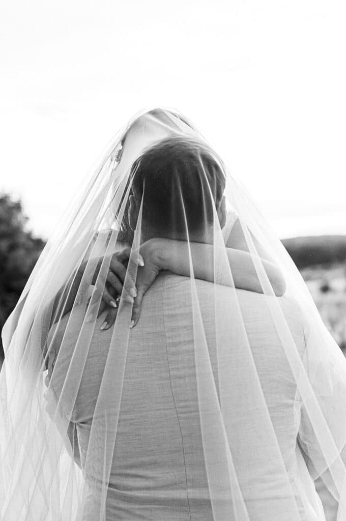 Photographe fine art mariage – couple de dos en noir et blanc sous un voile