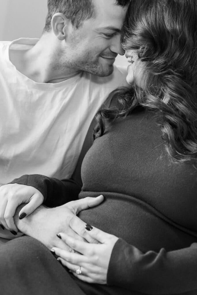 Séance photo maternité en intérieur, couple sur le canapé en noir et blanc